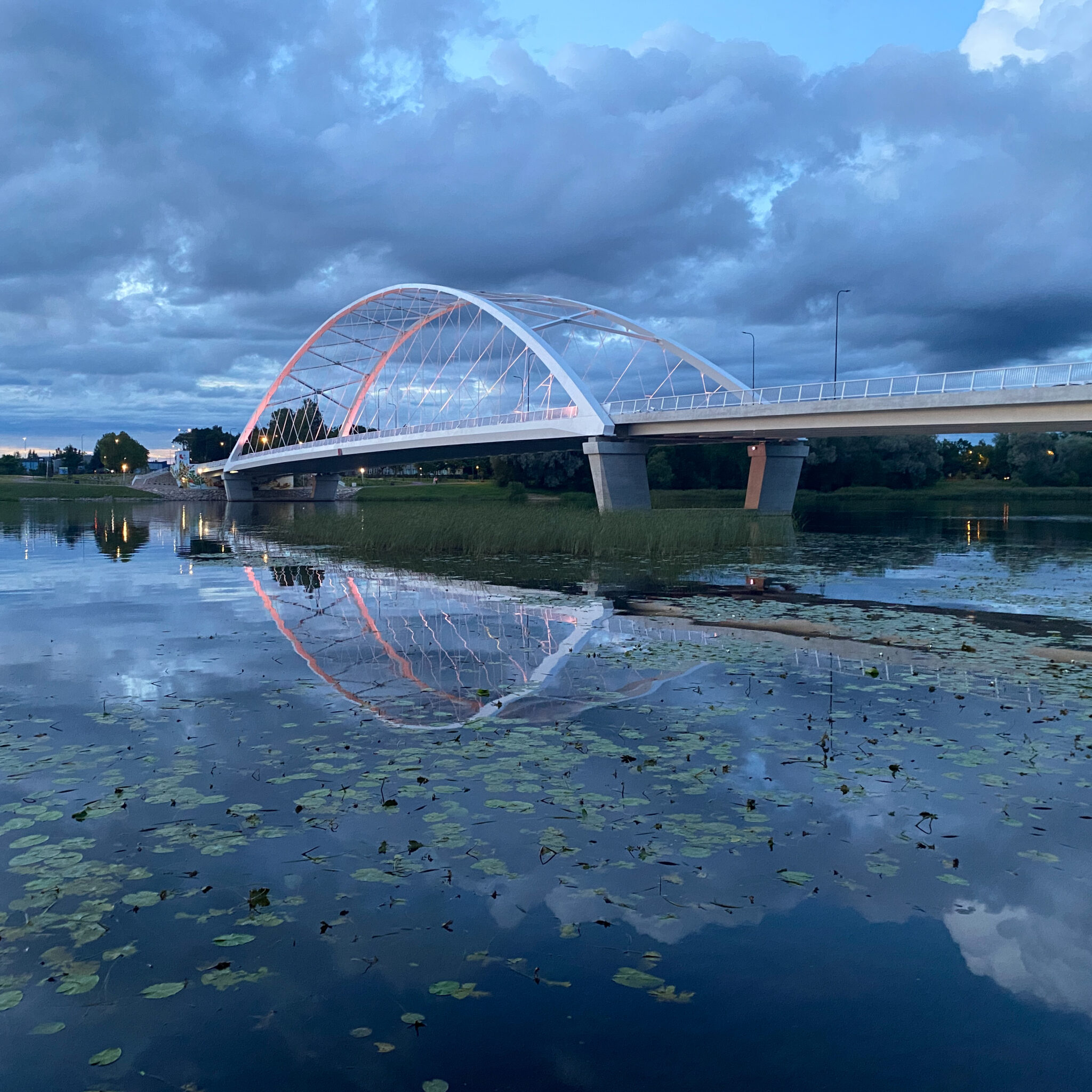 Kaasaegne sild ületab vaikse jõe videvikus.