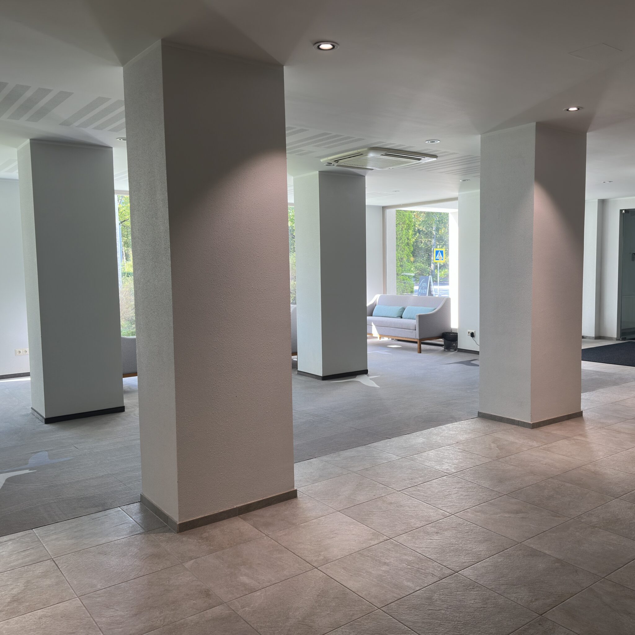 Avatud fuajee sammaste ja diivaniga.