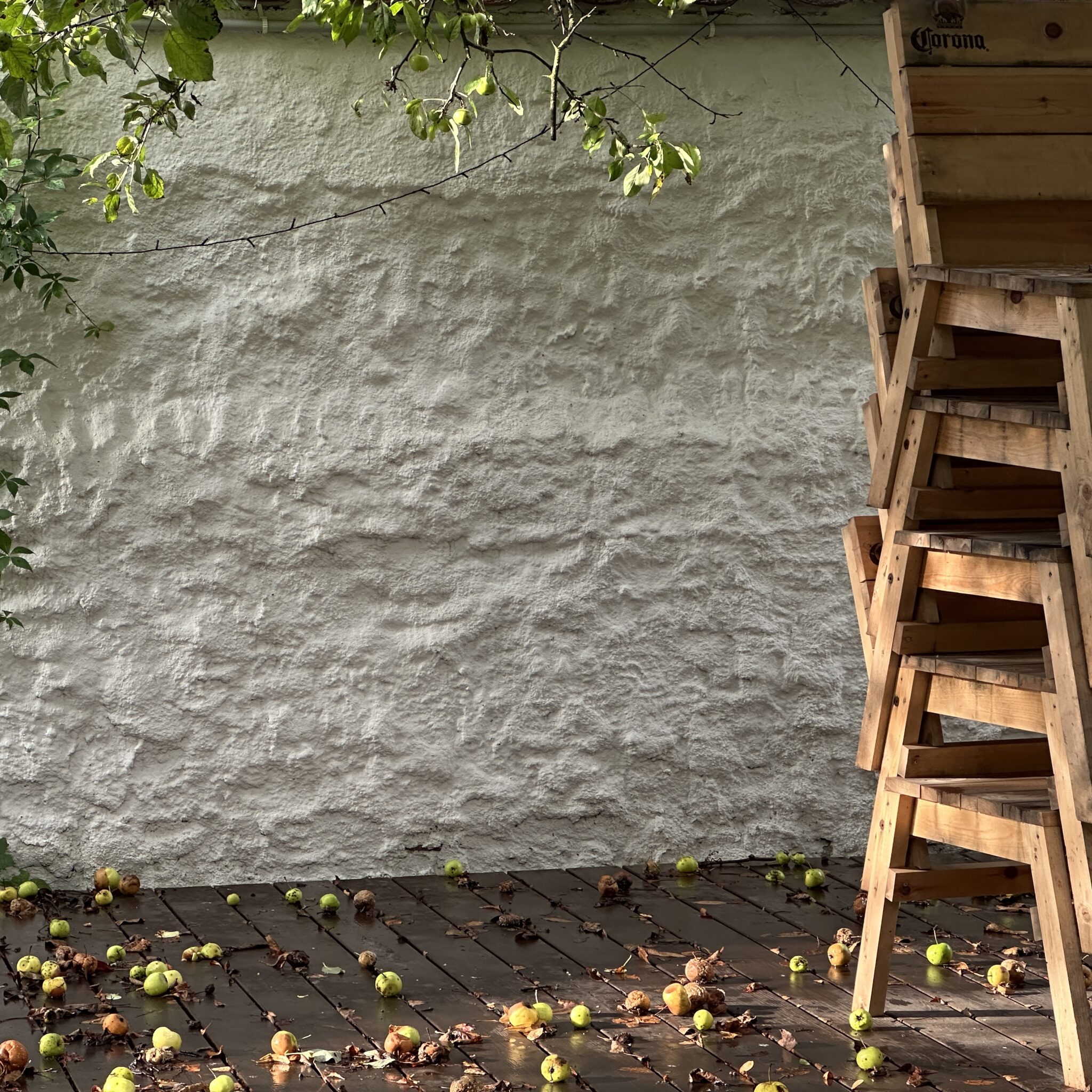 Puidust taburetid ja õunad puidust terrassil.