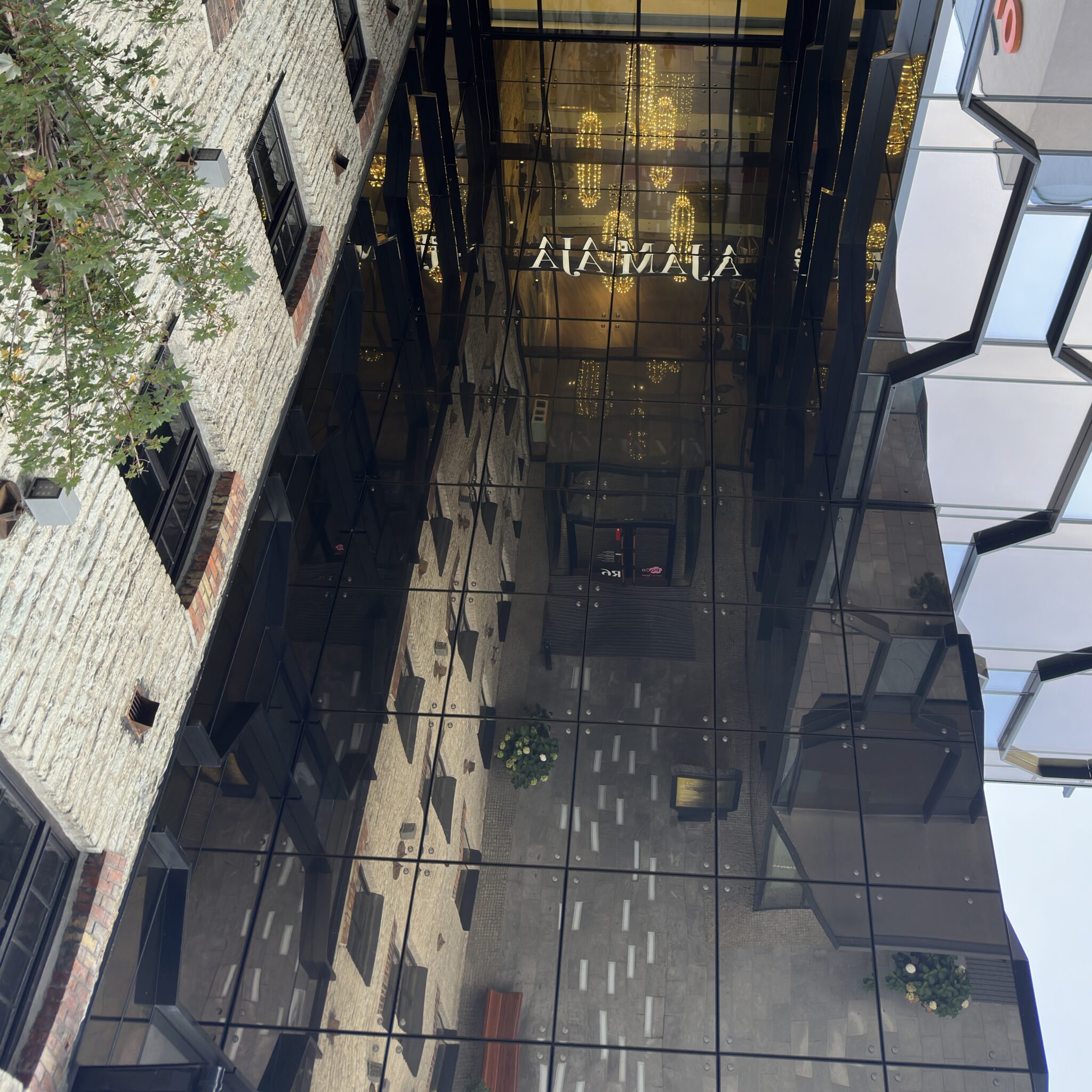 Kaasaegne klaashoone peegeldava fassaadiga ja sildiga „Alamala”.