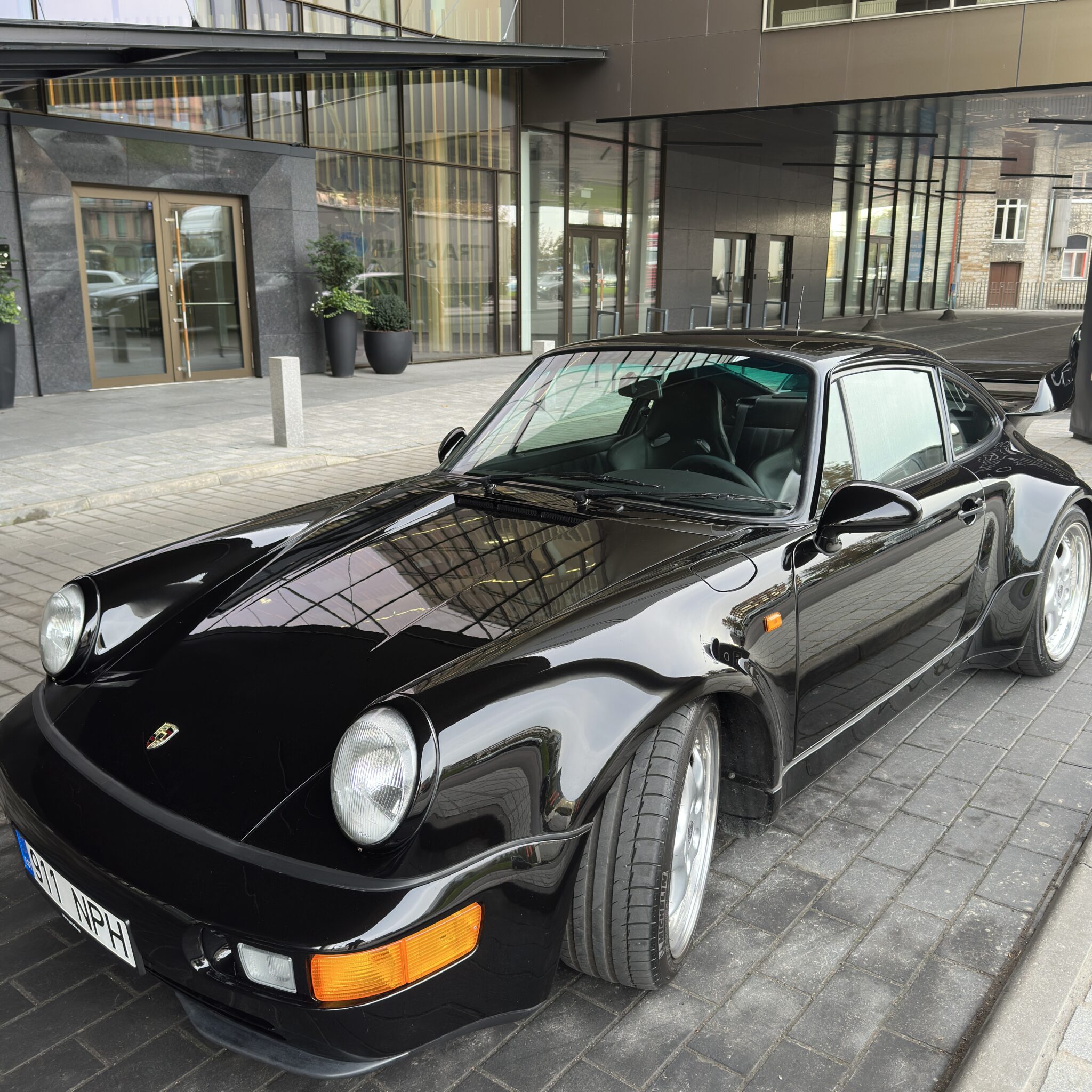 Must Porsche 911 pargitud kaasaegse hoone ees.