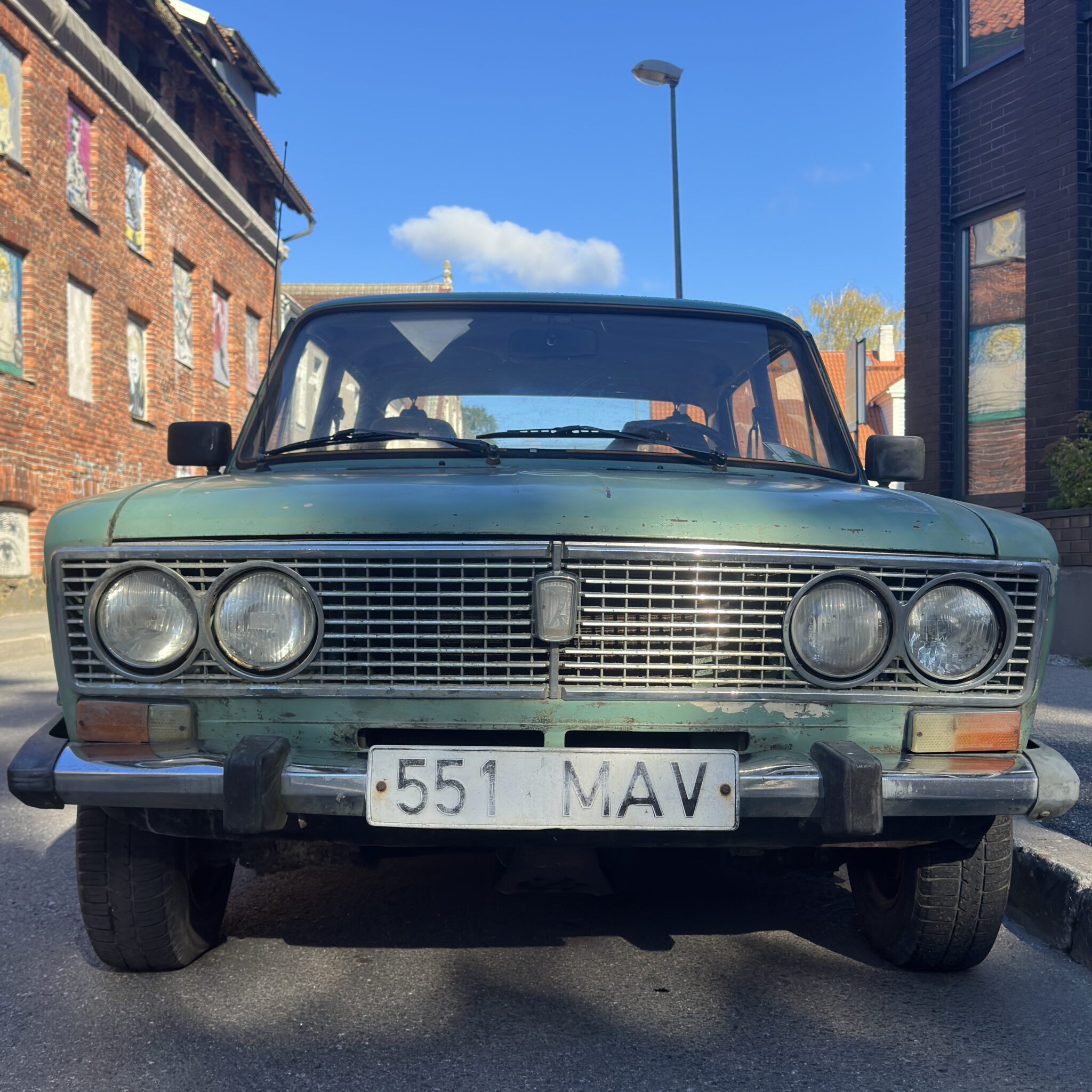 Roheline retroauto Lada numbrimärgiga pargitud tänaval.