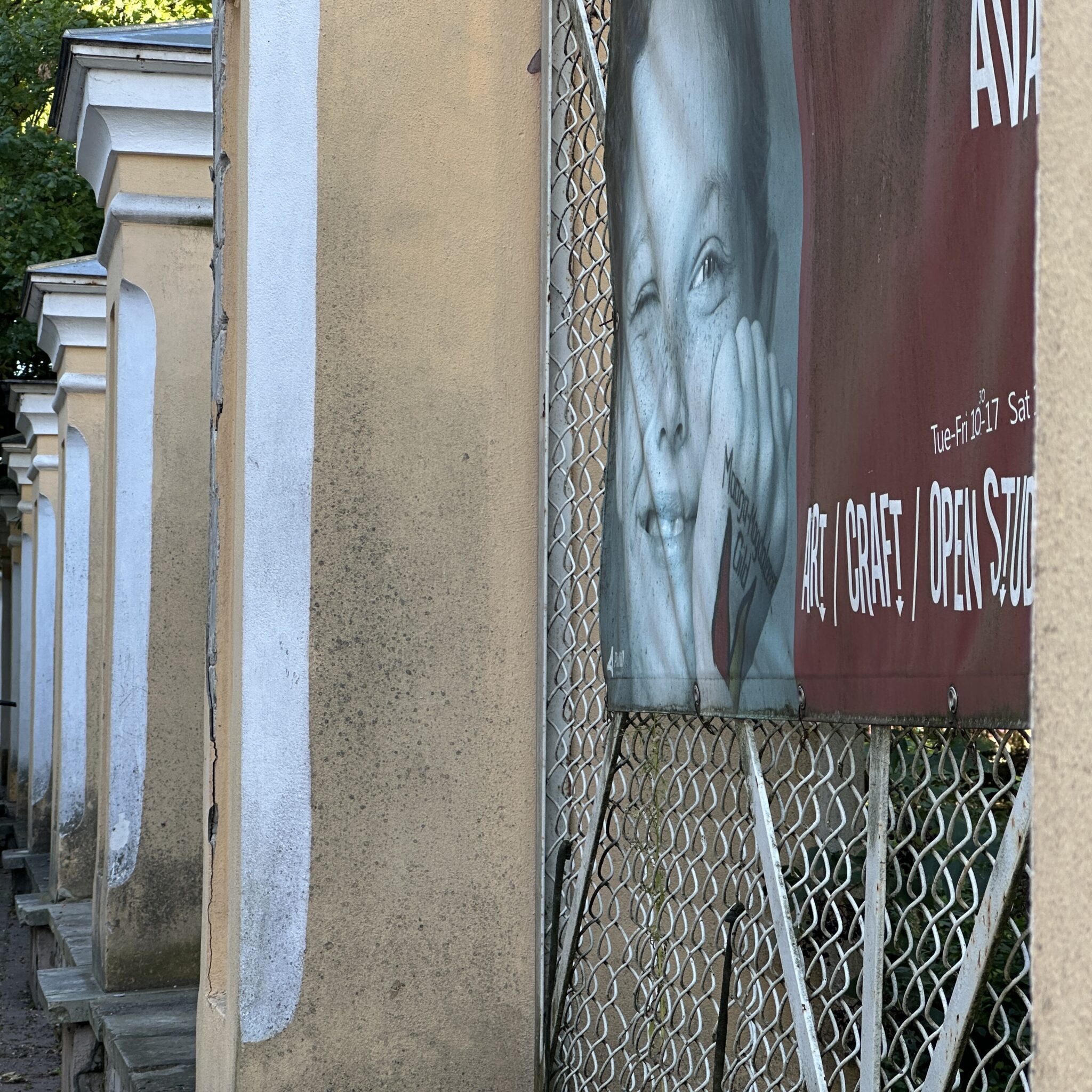 Bänner reklaamib kunsti- ja käsitööstuudiot valgete sammastega hoonel.