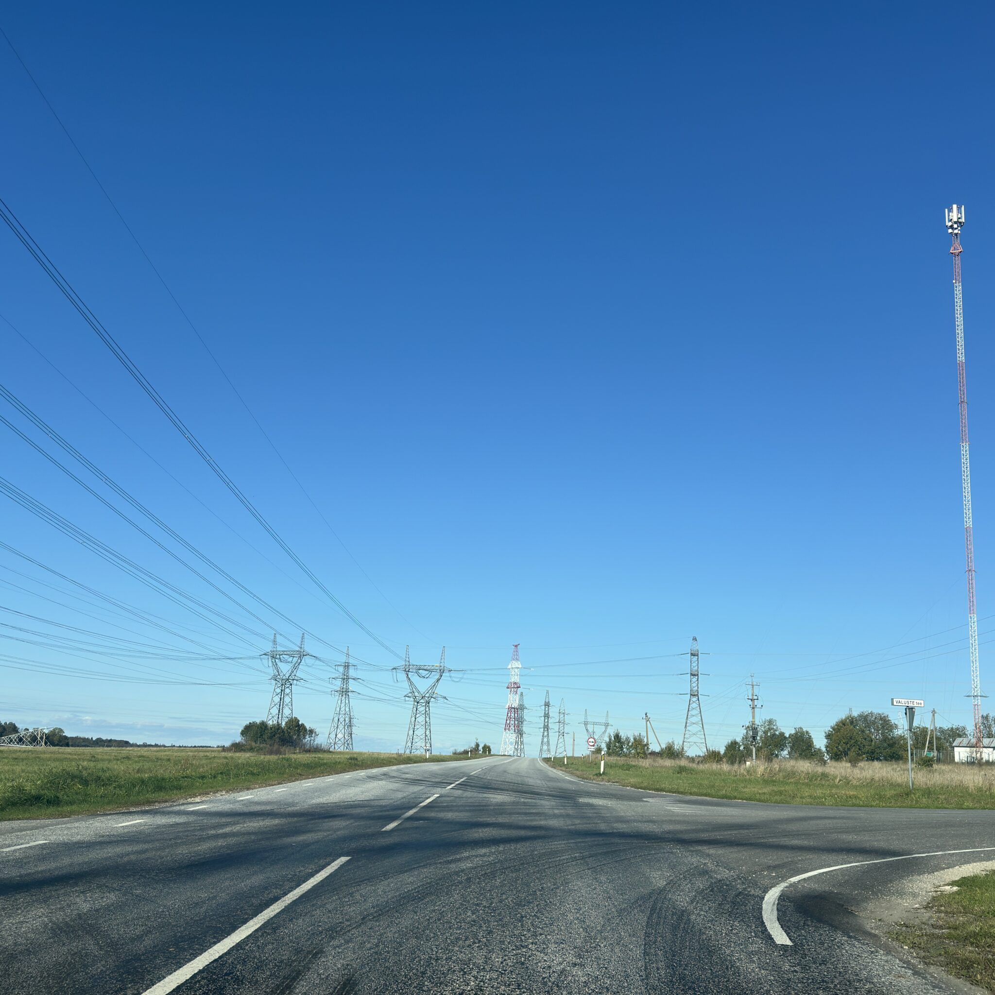 Tee ulatub kaugusse, kõrval elektriliinid ja mastid.