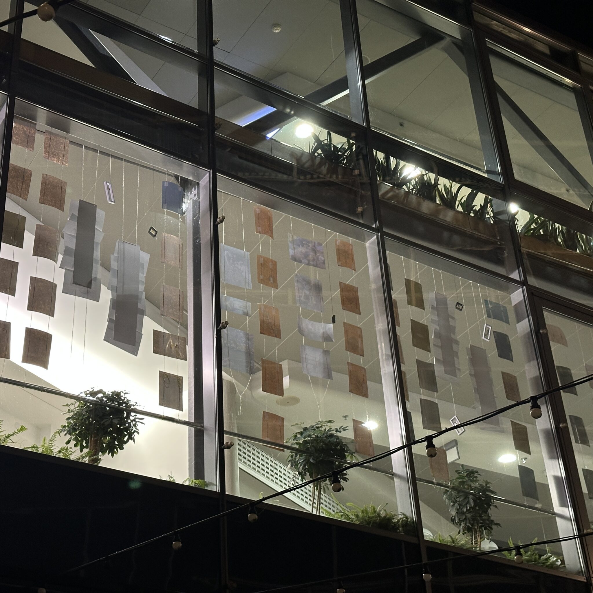 Kunstiinstallatsioon rippuvate paberite ja taimedega moodsas hoones.