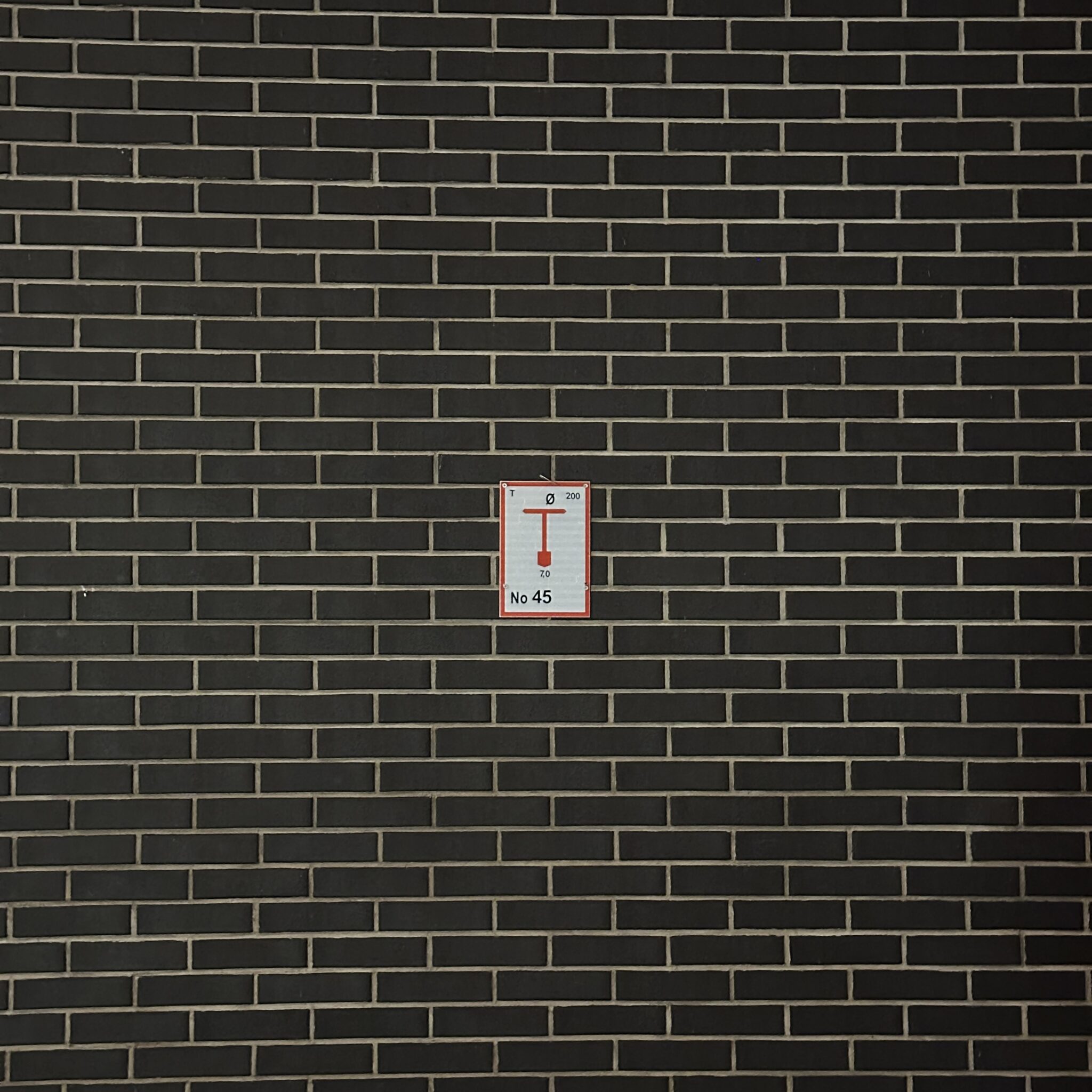 Punane ja valge silt mustal tellisseinal.