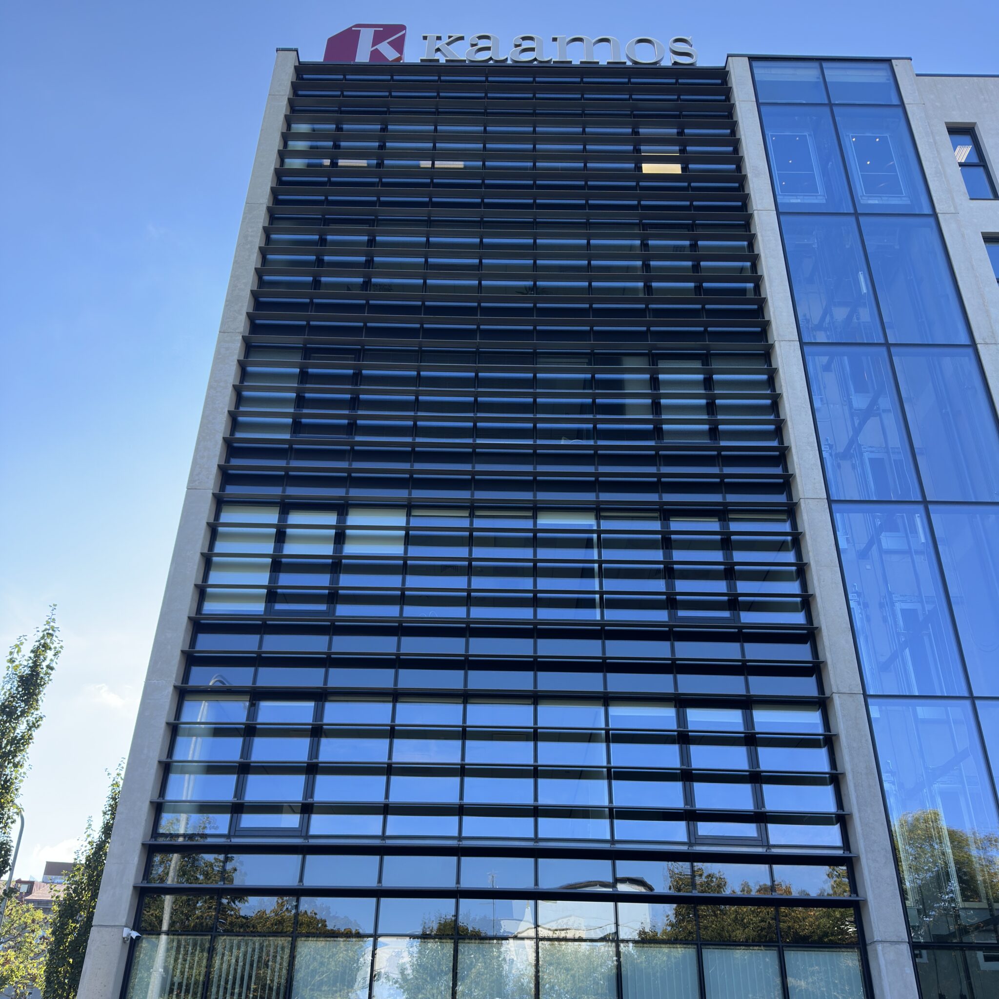 Kaamos hoone klaasfassaadiga ja selge taevas.