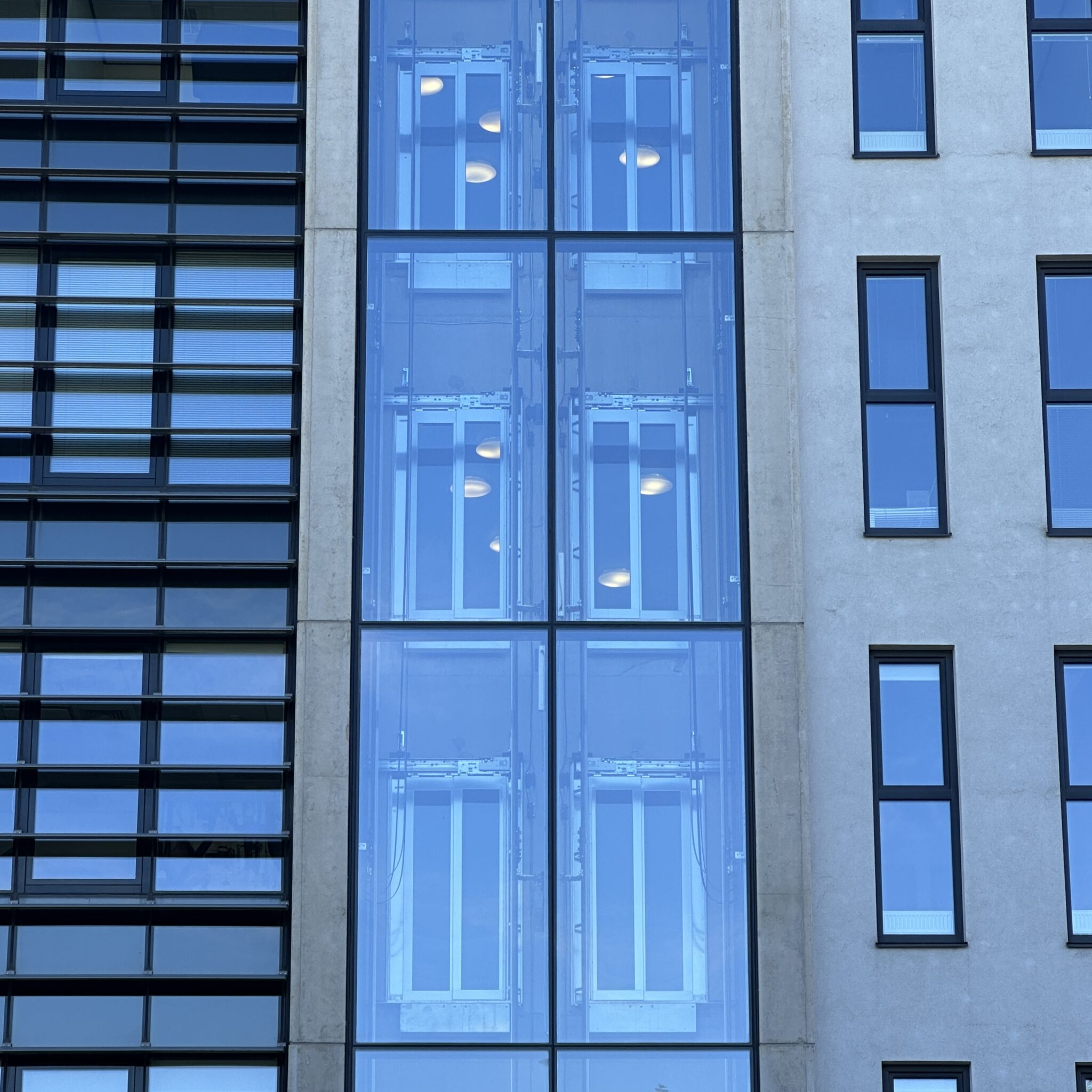 Kaasaegne hoone peegeldavate klaasakende ja mustade raamistikuga.