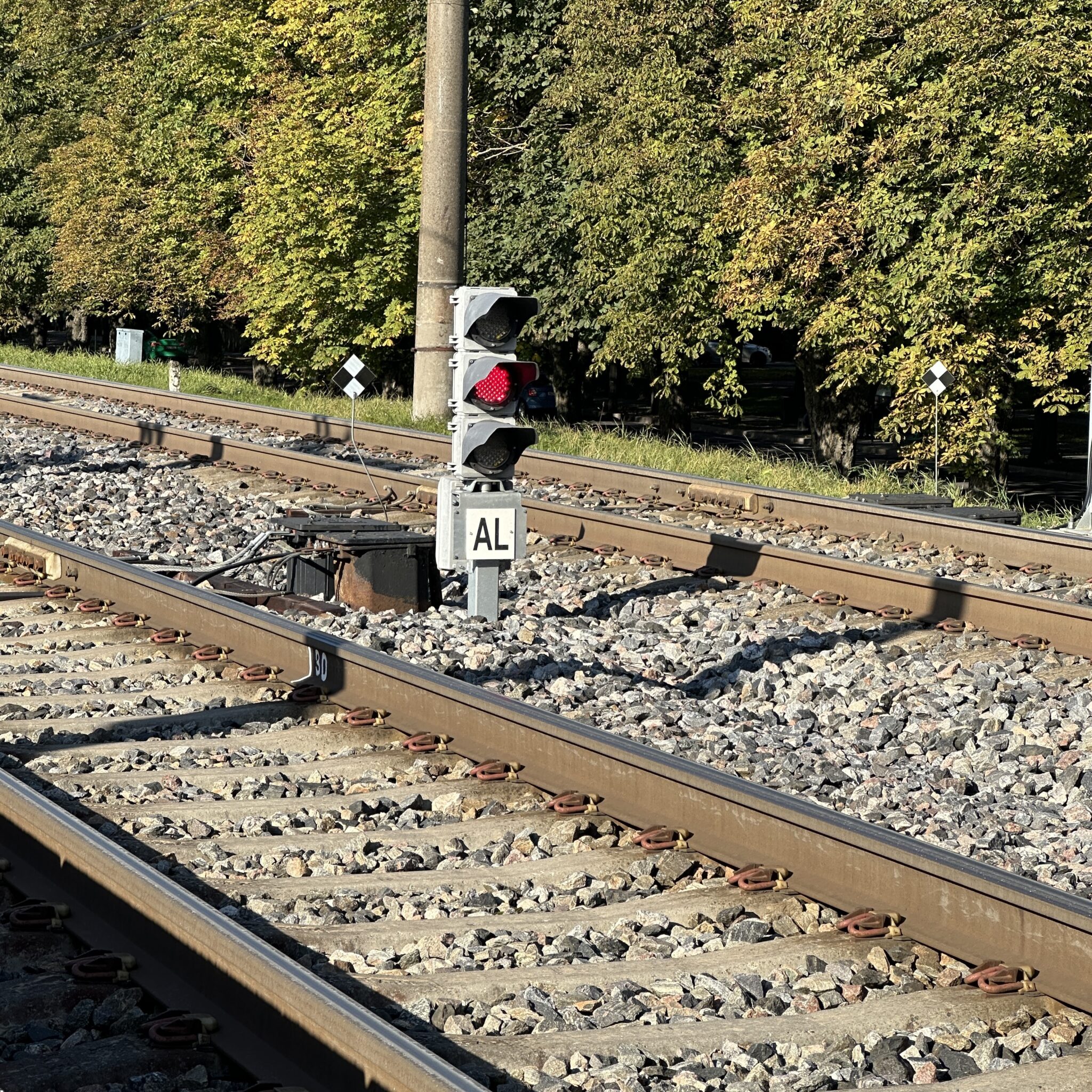 Raudtee ja punane tuli, kõrval silt „AL”, metsane ümbrus.