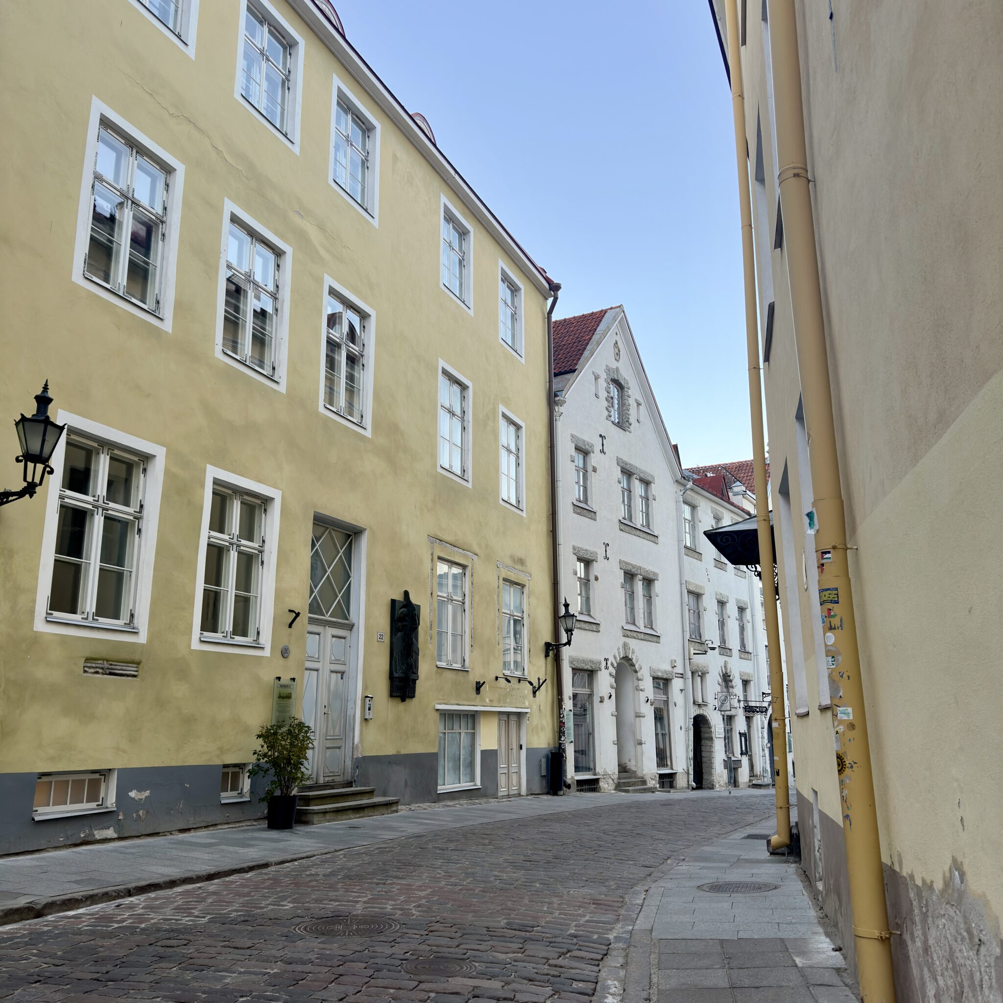 Kitsas tänav Tallinnas kollaste ja valgete hoonetega.