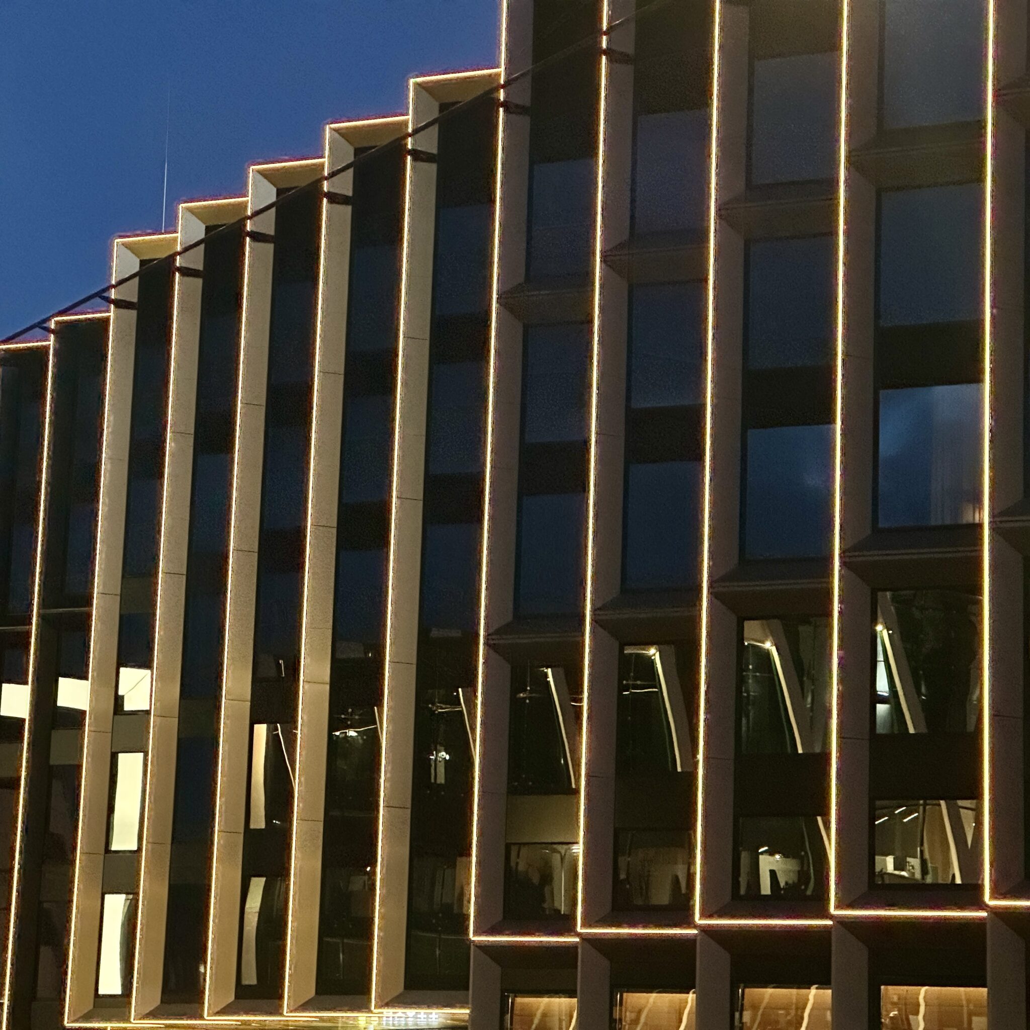 Kaasaegne hoone valgustatud akendega öös.