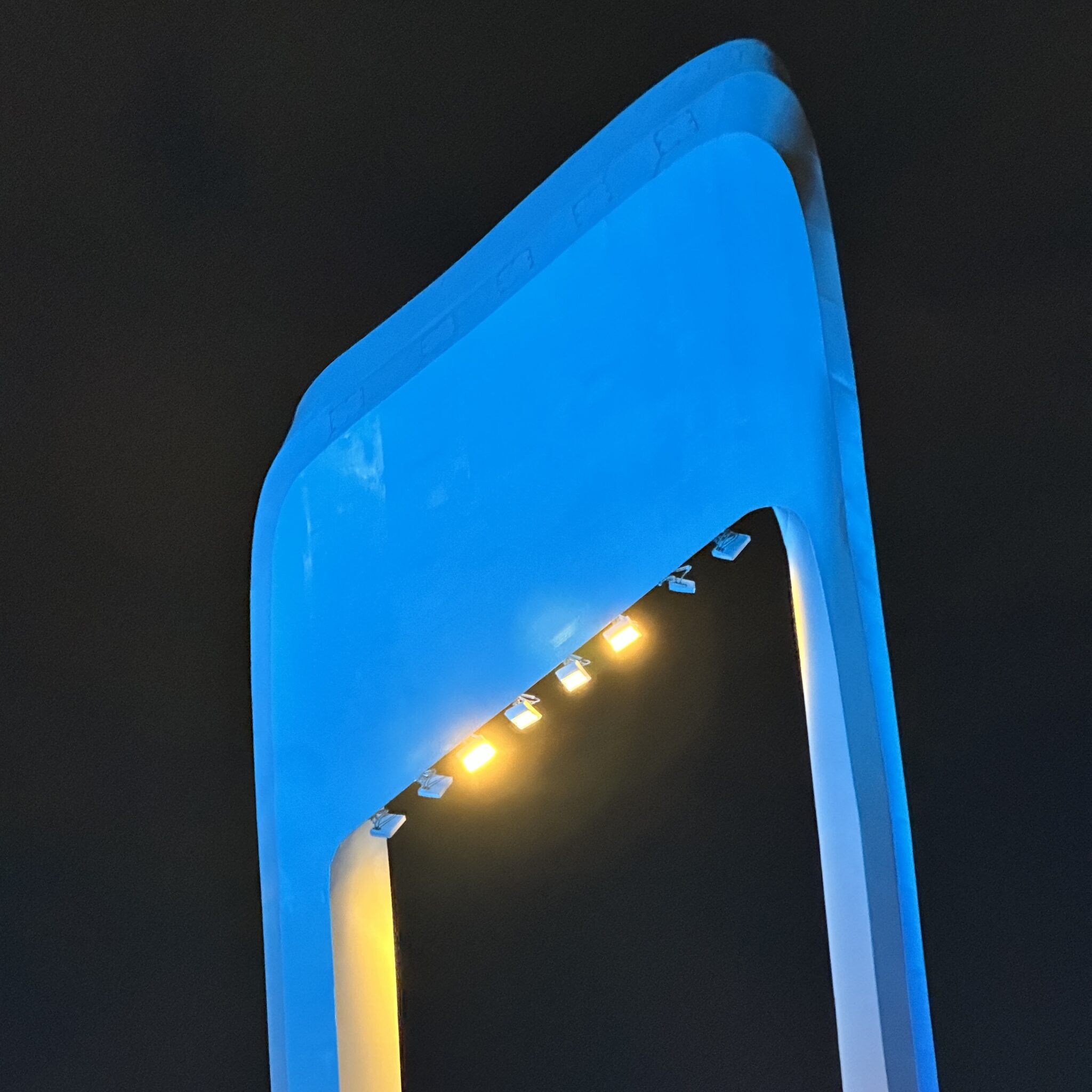 Kaasaegne sinine hoone kollaste tuledega vundamendil.