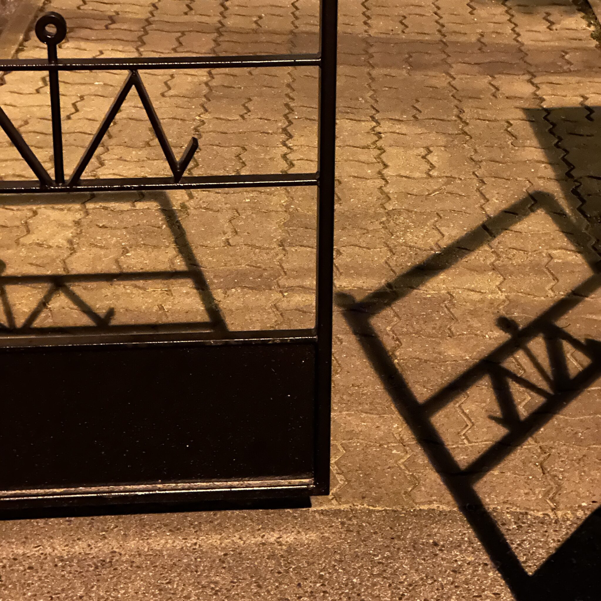 Metallvärav heidab varju plaaditud kõnniteele.