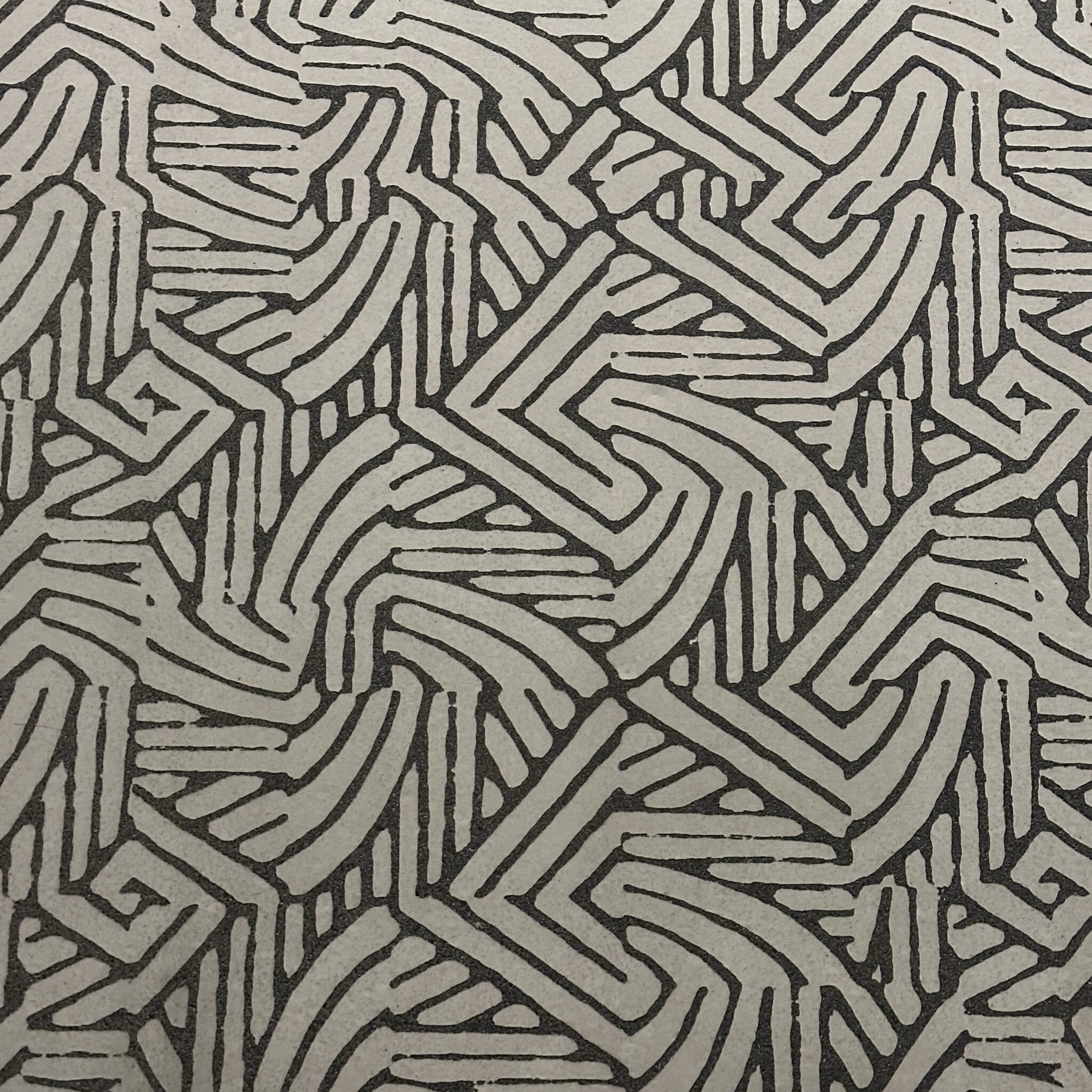 Geomeetriline põimuv muster tekstureeritud pinnal.