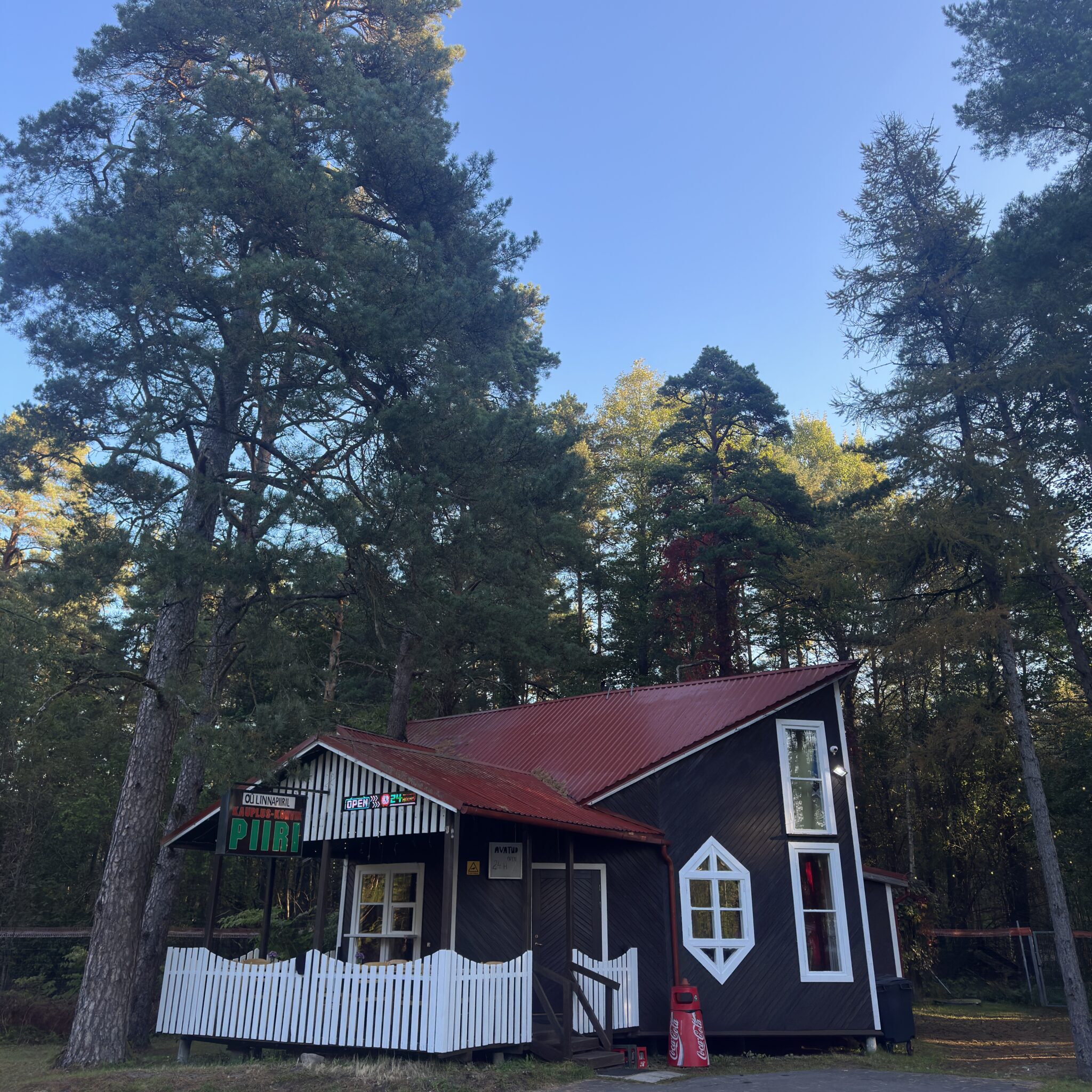 Punase katuse ja valge aiaga palkmaja metsas.