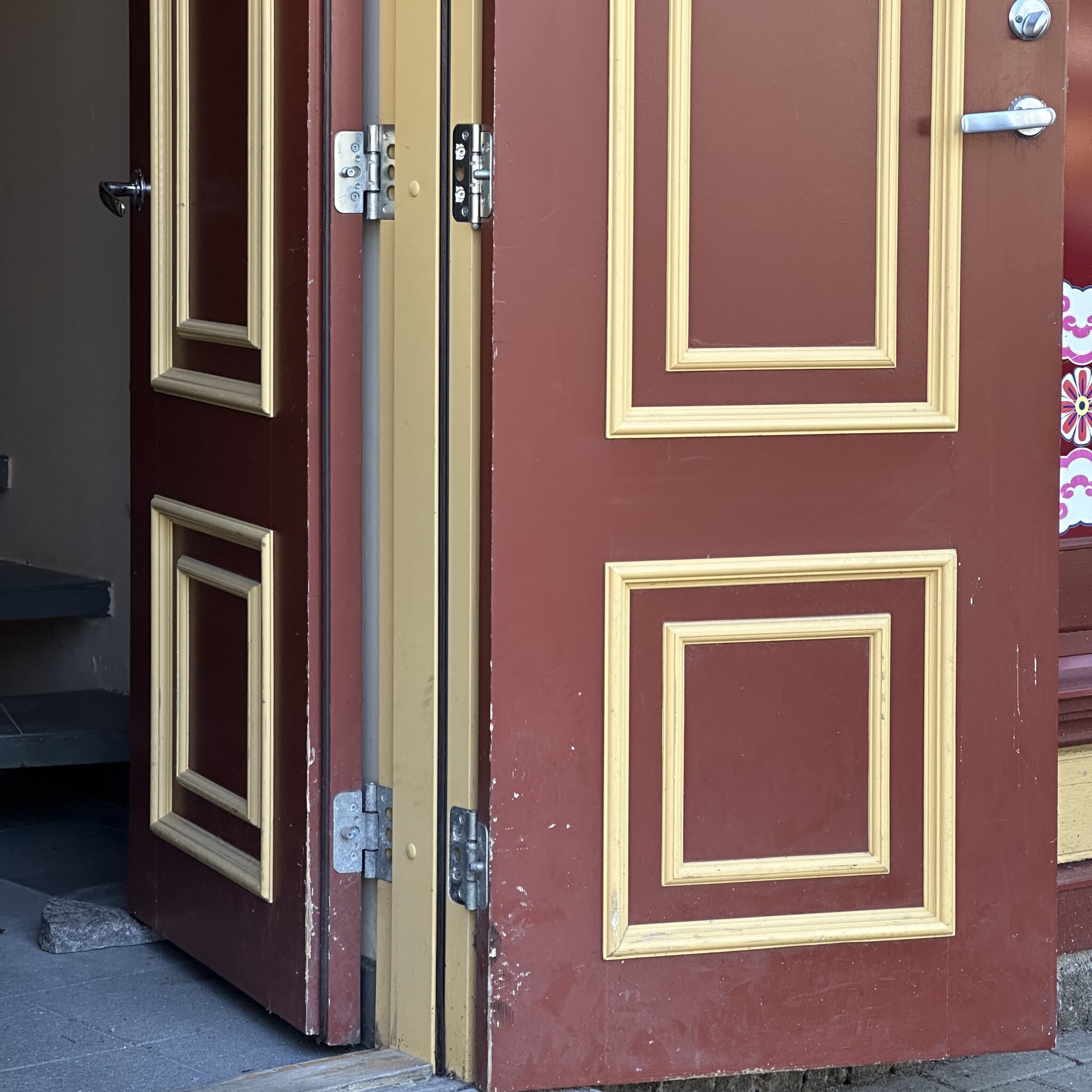 Punane uks kuldse raamiga ja metallist käepidemega.