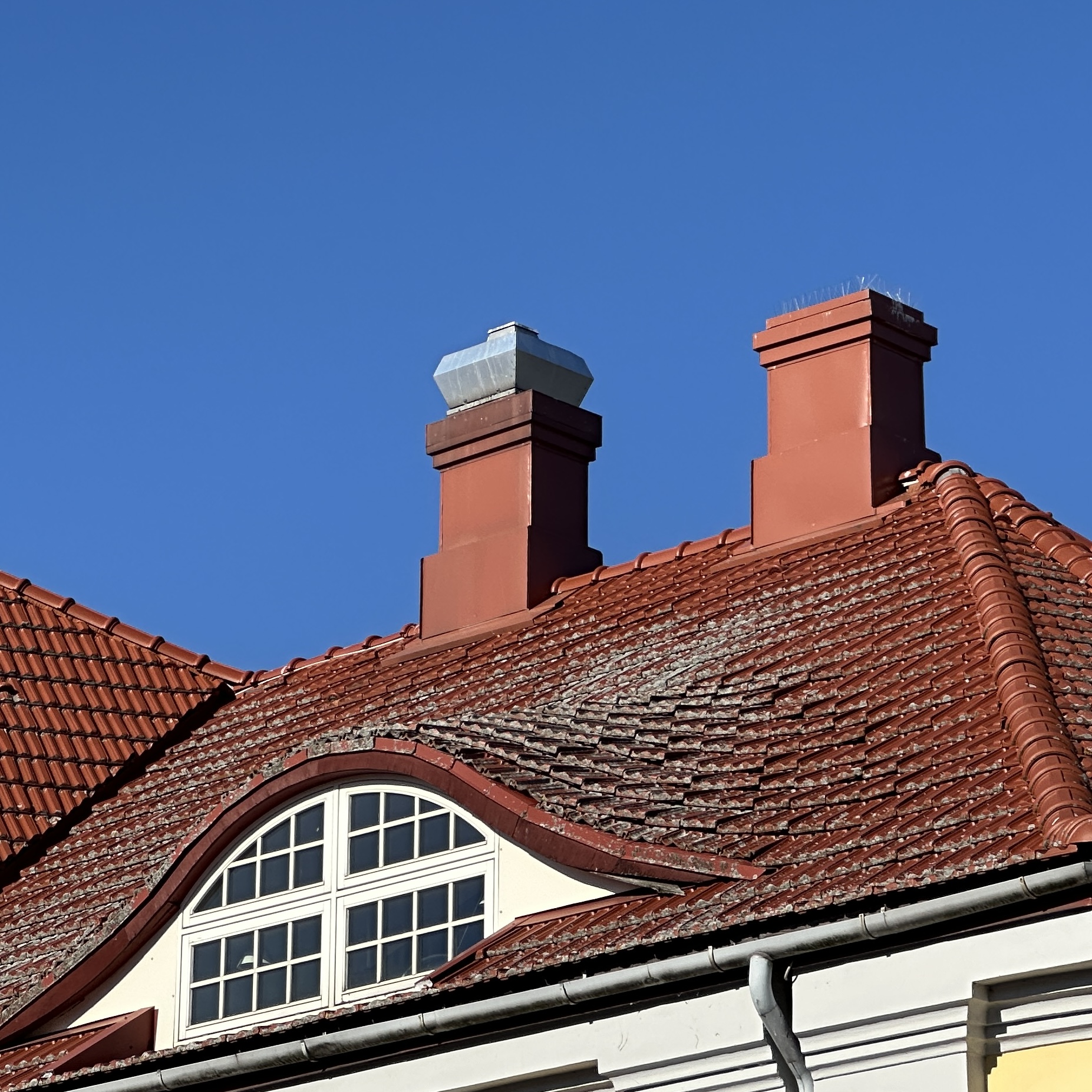 Kaks punast korstnat katusekivide taustal.