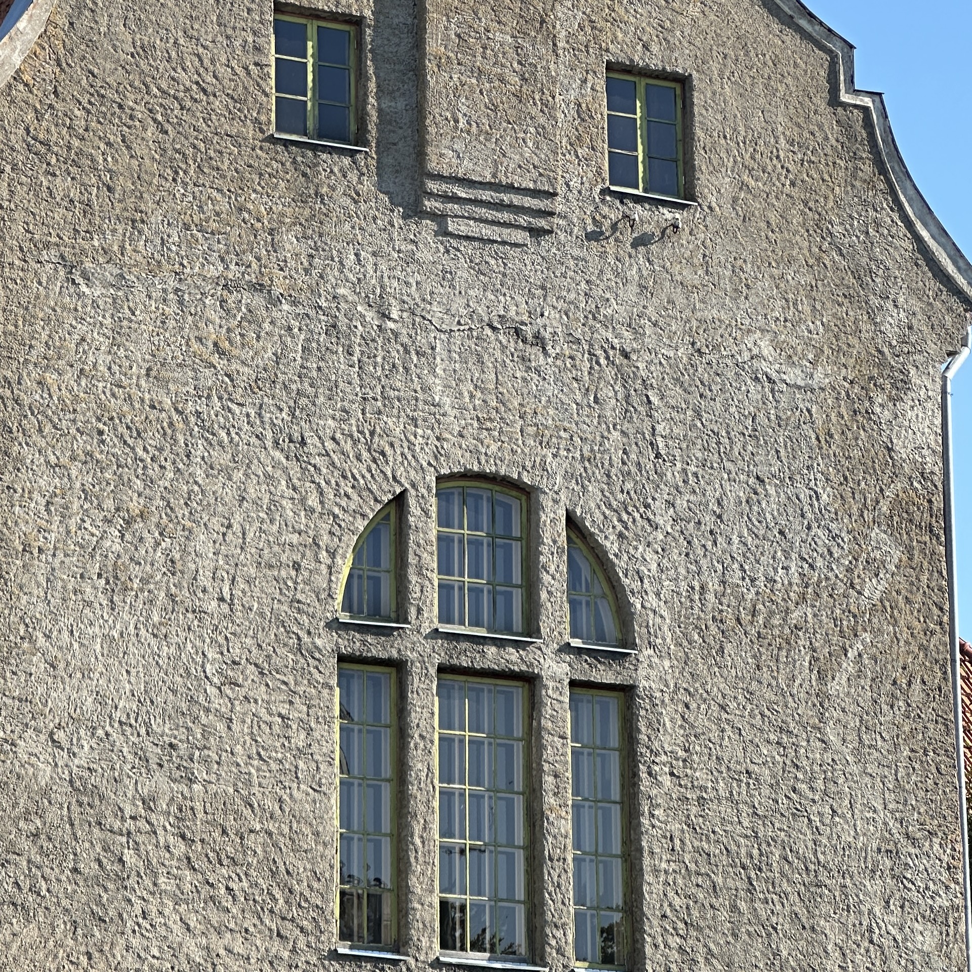 Hall kivist hoone kaarjate akendega.