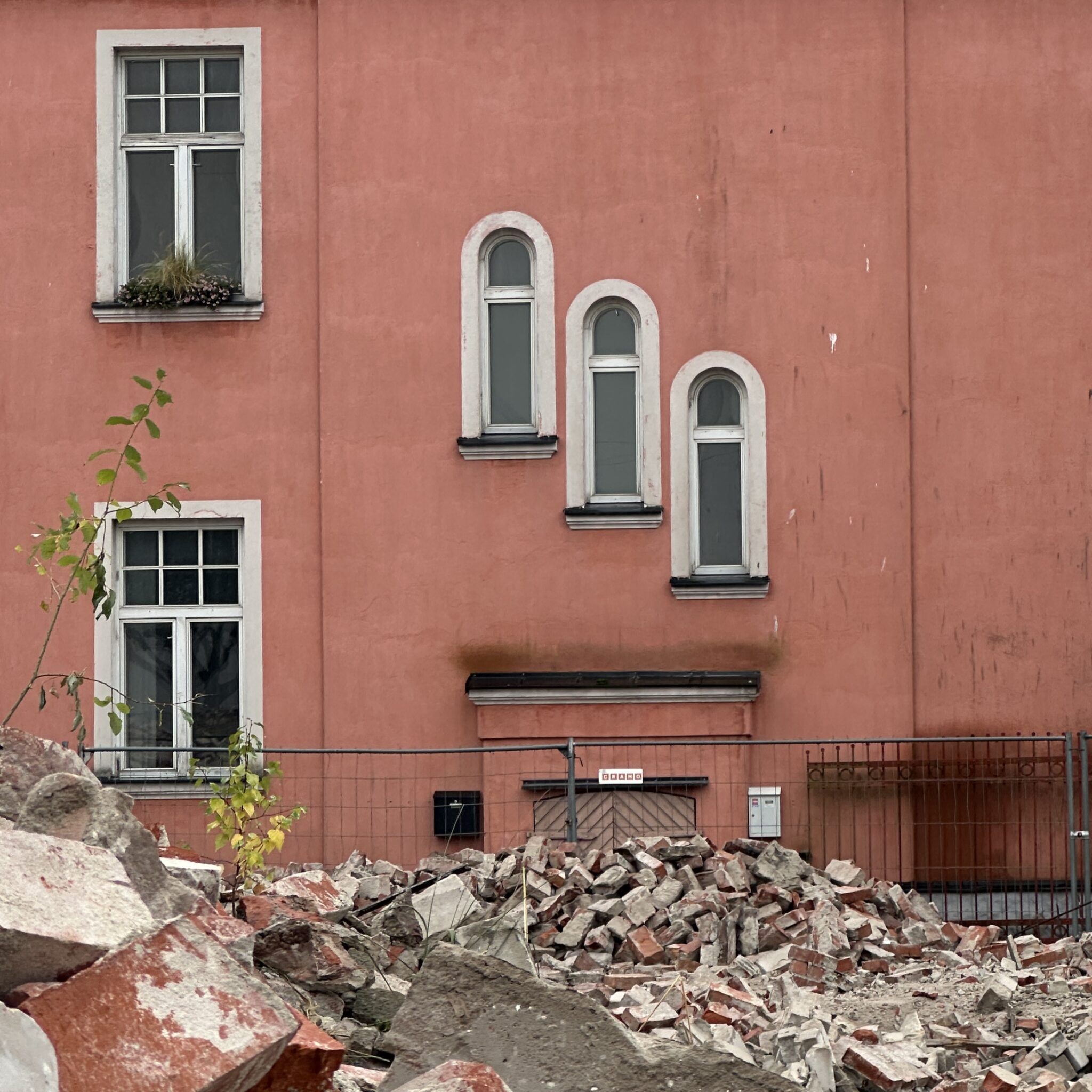 Punane hoone kaarjate akendega ja ees olev tara.