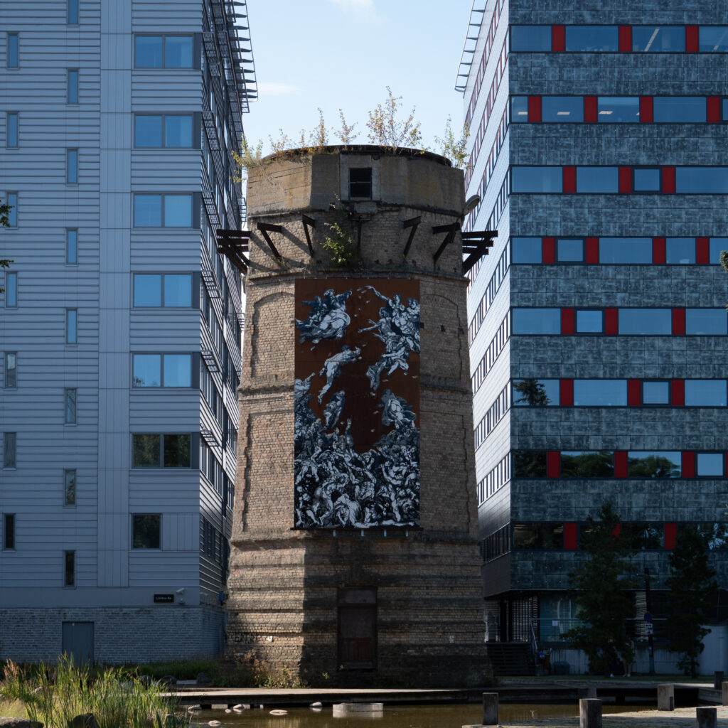 Kõrge tellistest torn seinamaalinguga, kahe moodsa hoone vahel.