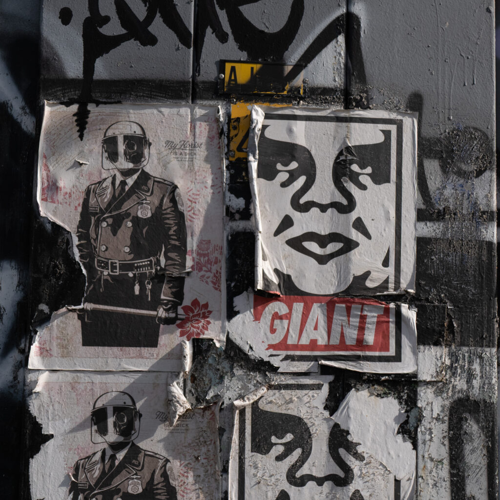 Seinale kleebitud kulunud plakatid, üks neist politseinikuga.