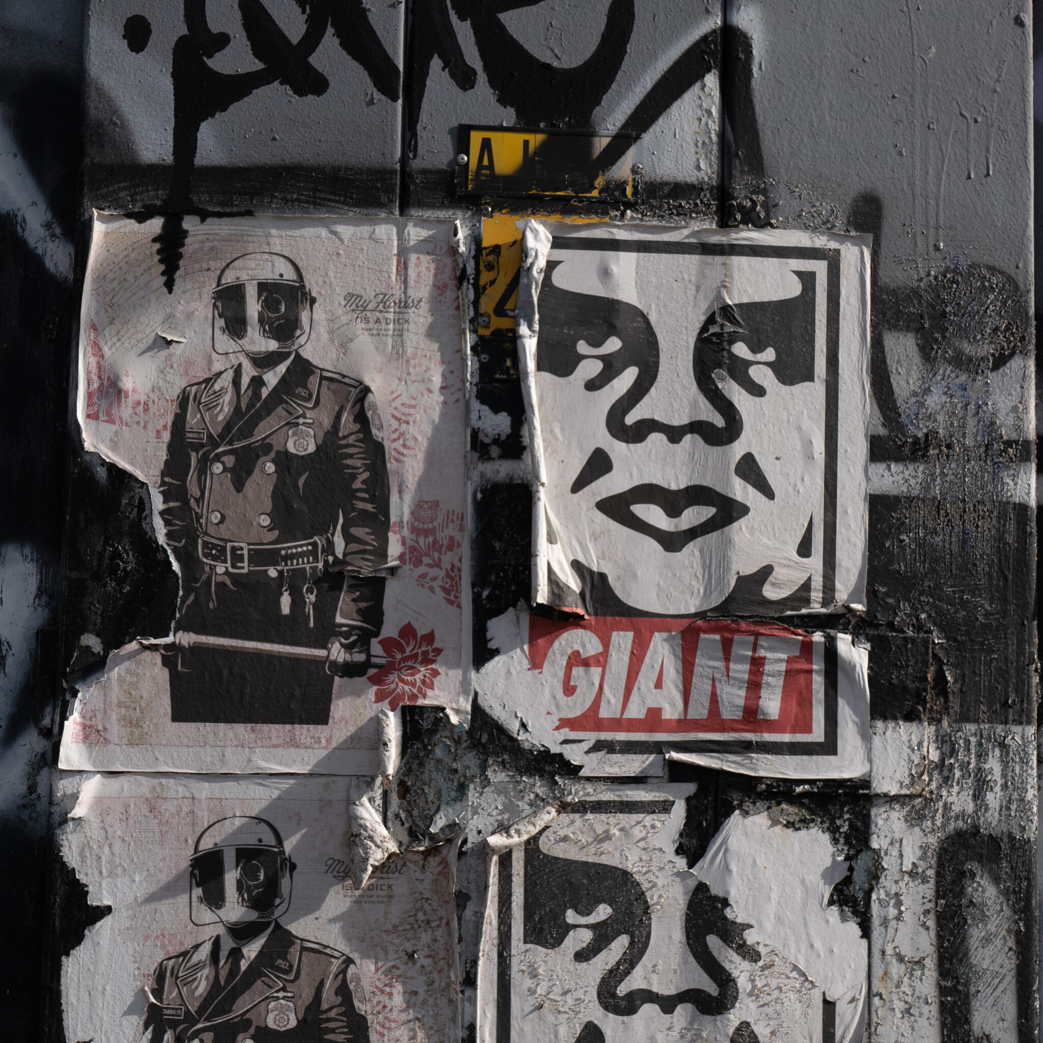 Seinale kleebitud kulunud plakatid, üks neist politseinikuga.