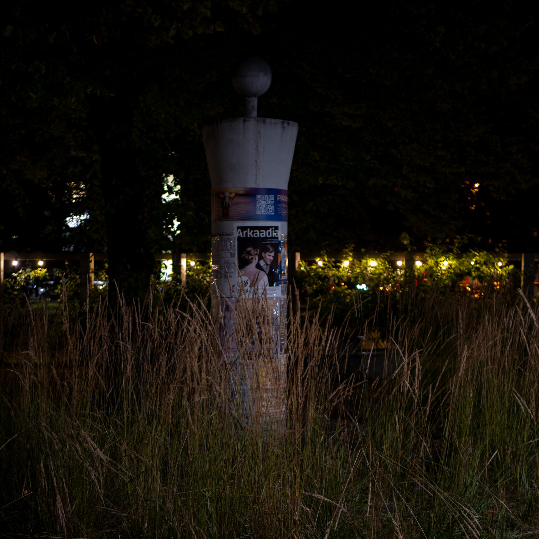 Kõrge silindrikujuline torn palliga tipus seisab öises rohus.