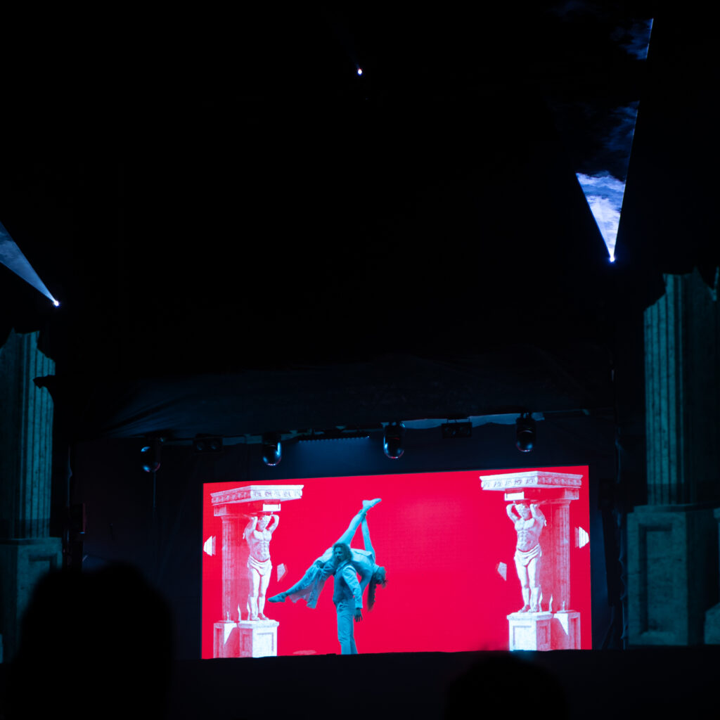 Kaks akrobaati esinevad punase taustaga laval.