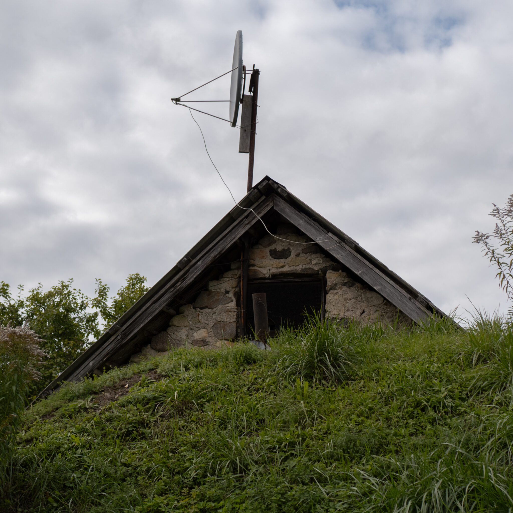 Rustikaalne kivist hoone satelliiditaldrikuga katusel.