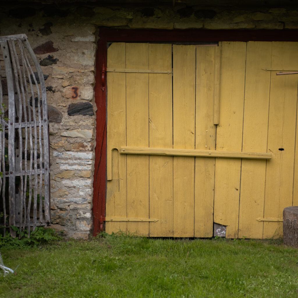 Kollane lauda uks punase äärise ja kiviseinaga.