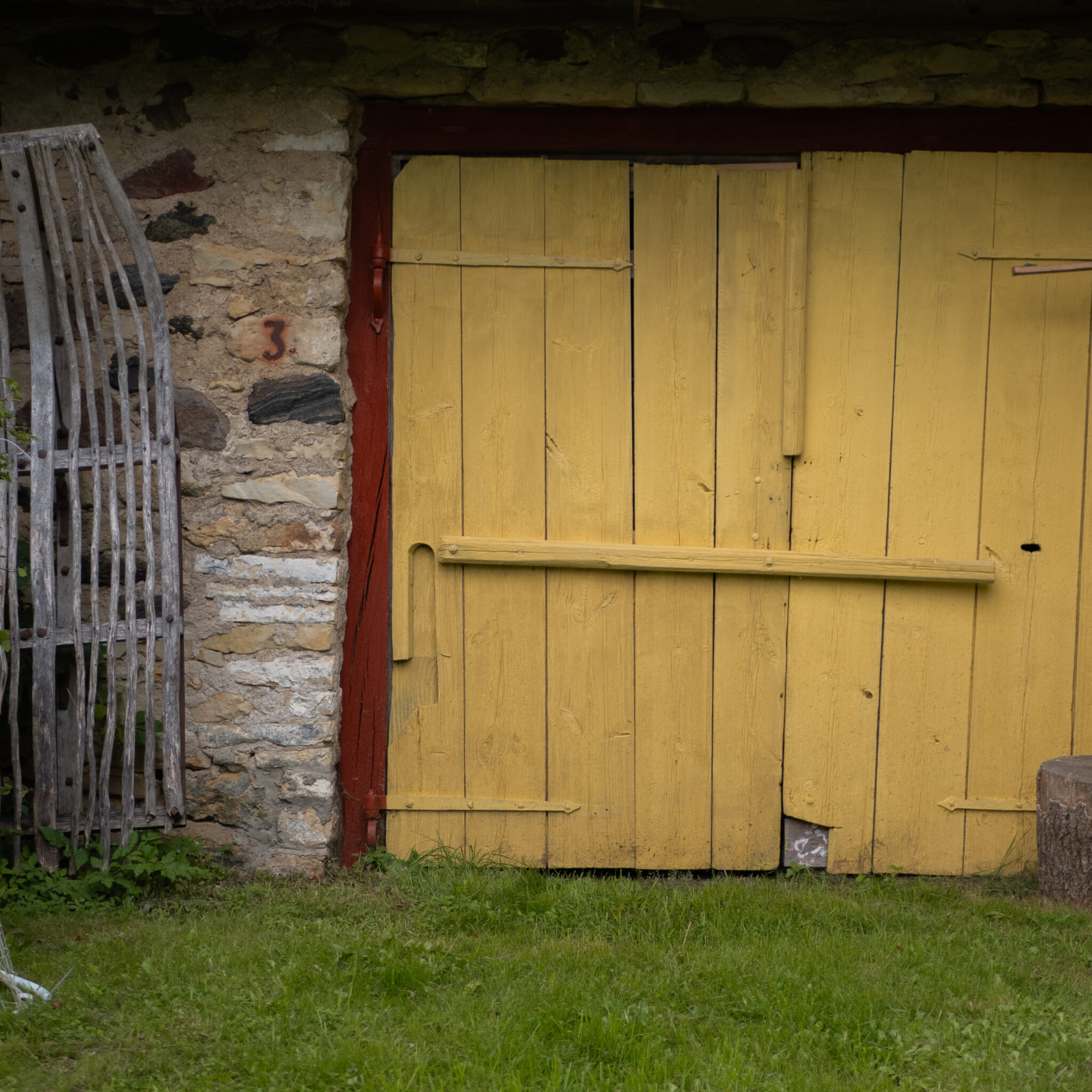 Kollane lauda uks punase äärise ja kiviseinaga.