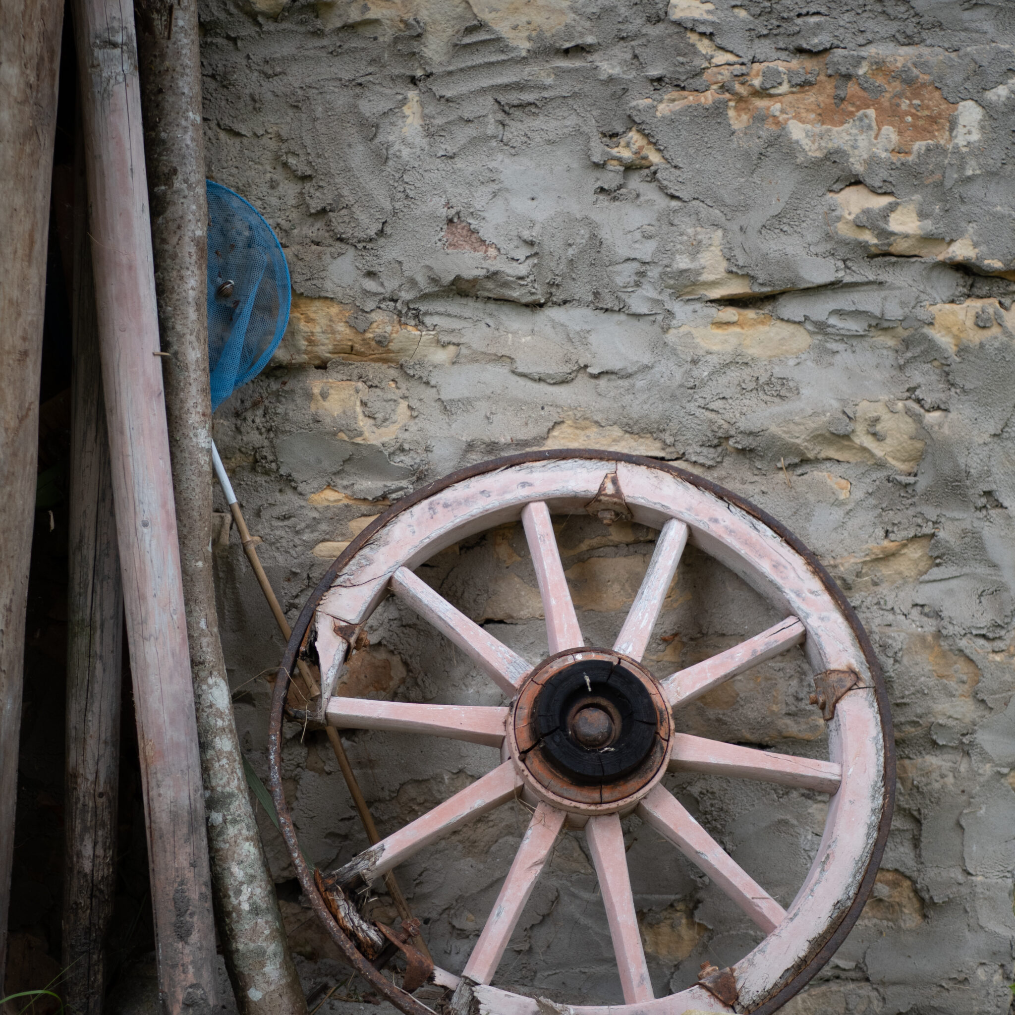 Vana puidust ratas kulunud seina ees.