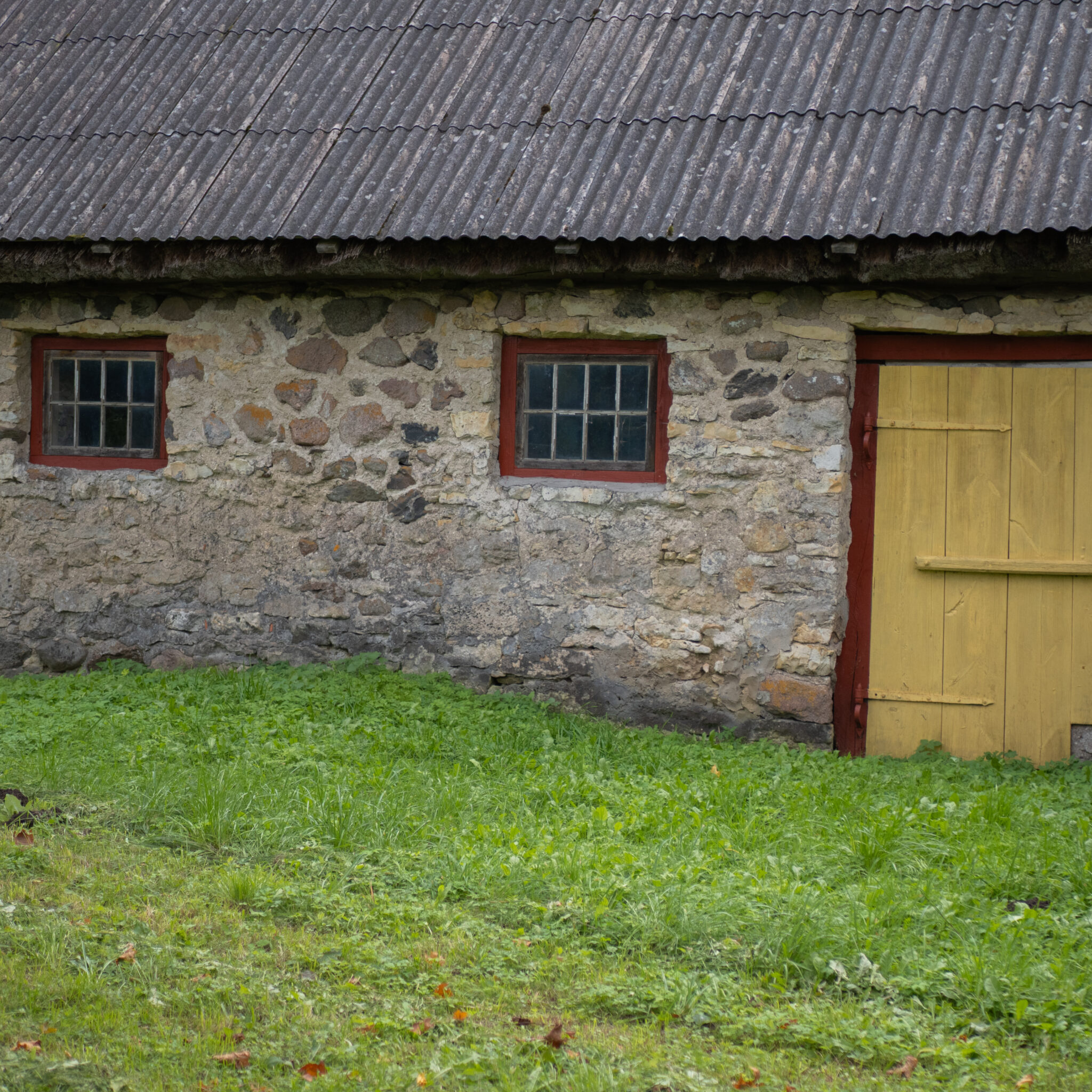 Rustikaalne kivist ait kollaste uste ja akendega.