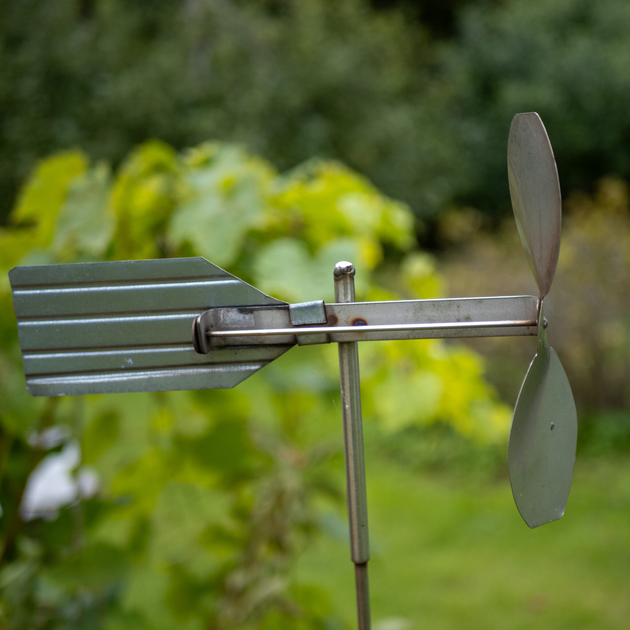 Metallist tuuleveski aias rohelise tausta ees.