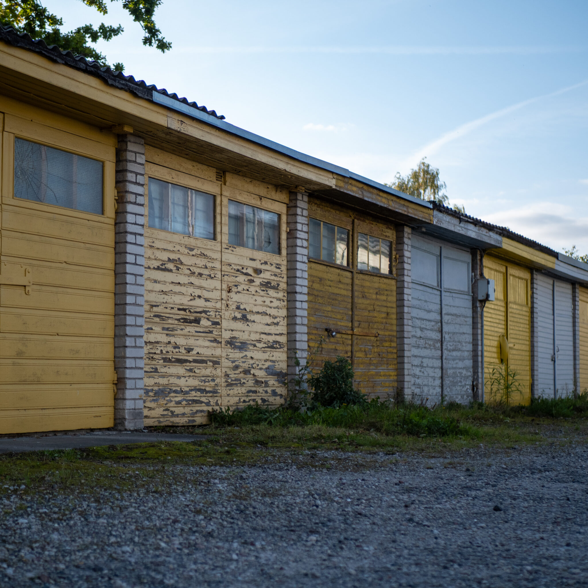 Rida kulunud garaaže kollaste, valgete ja hallide ustega.