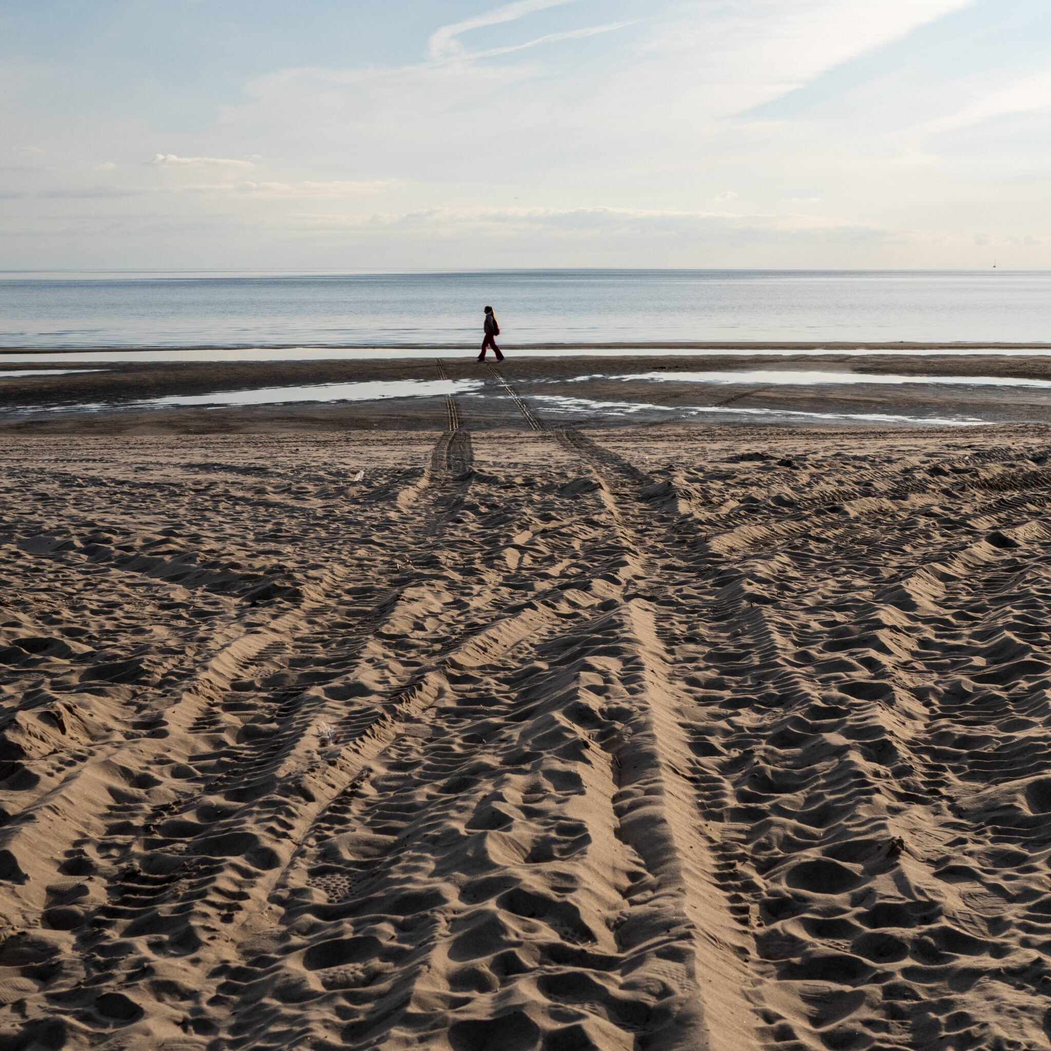 Üksik inimene kõnnib mööda liivaranda mere poole.