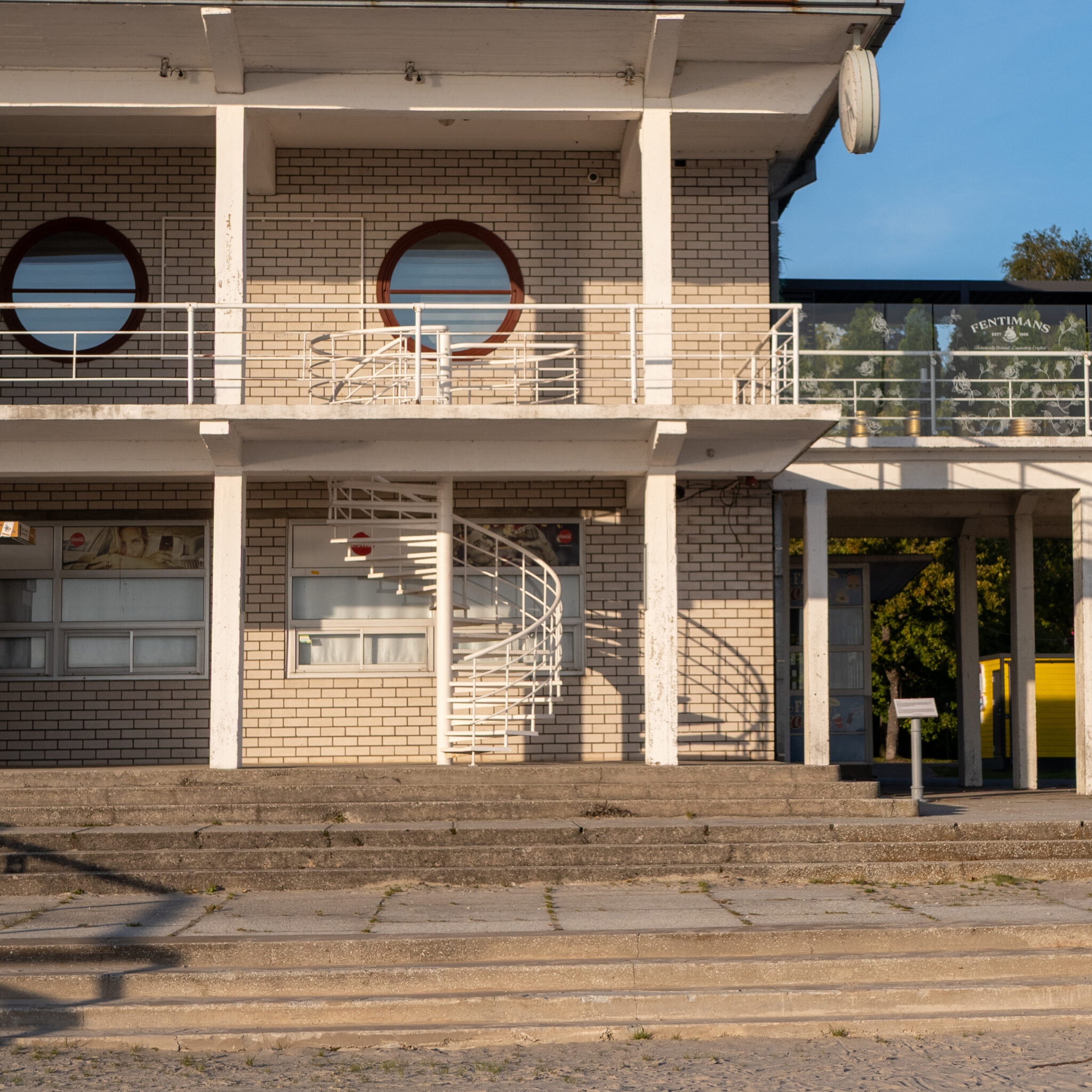 Kahekorruseline hoone keerdtrepi ja ümarate akendega.