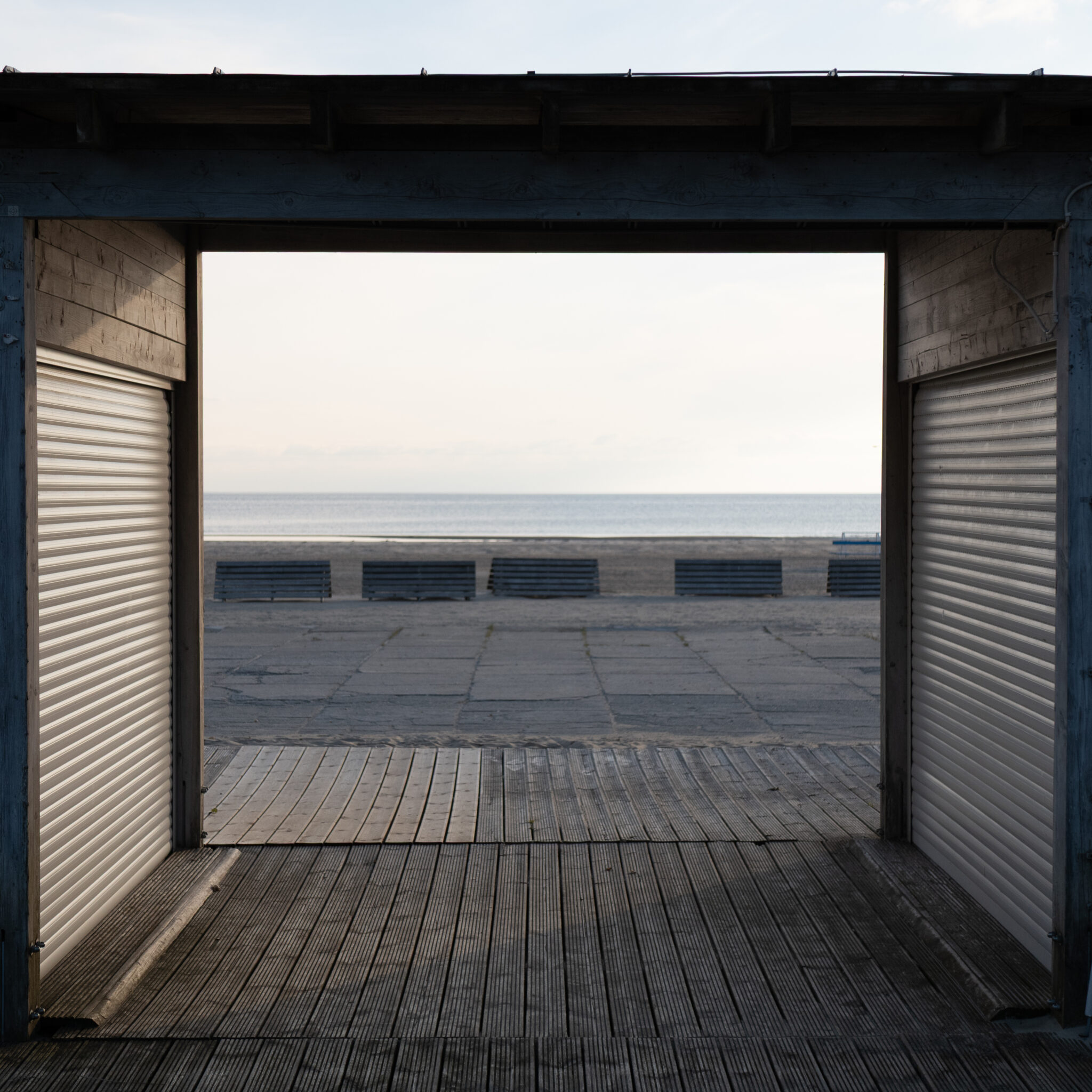 Puidust ehitis luukidega viib rannale, kus on pingid ja meri.