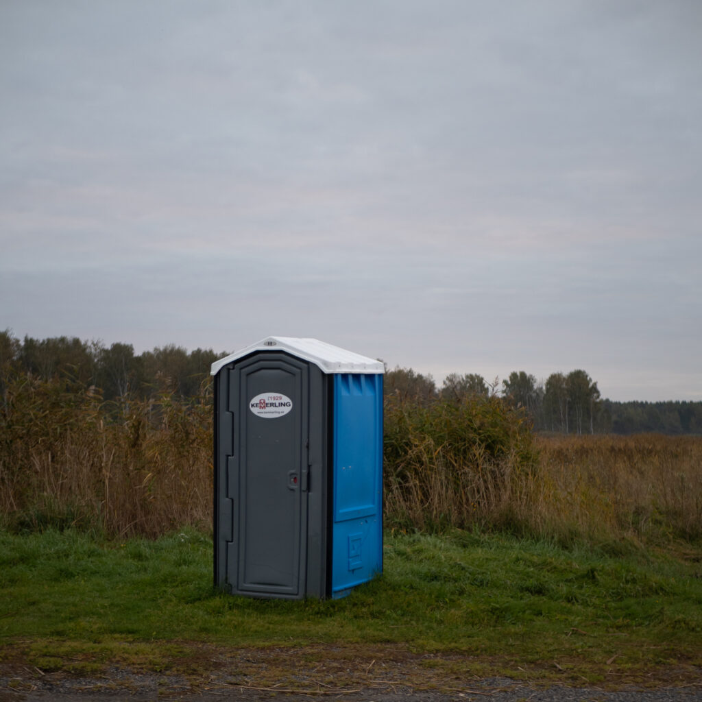 Välikäimla seisab rohusel väljal, ümberringi puud.