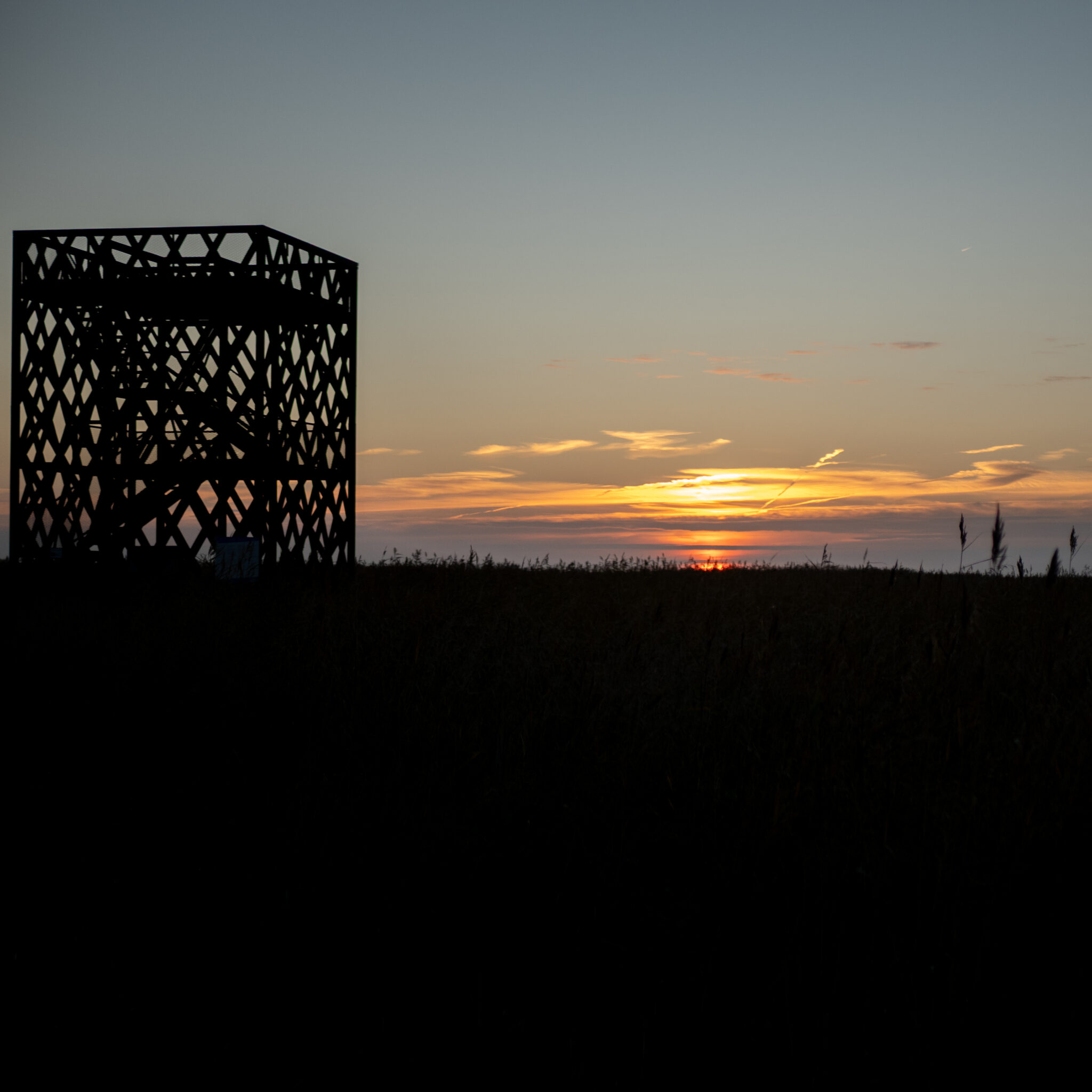 Metallkonstruktsiooni siluett loojangutaeva taustal.