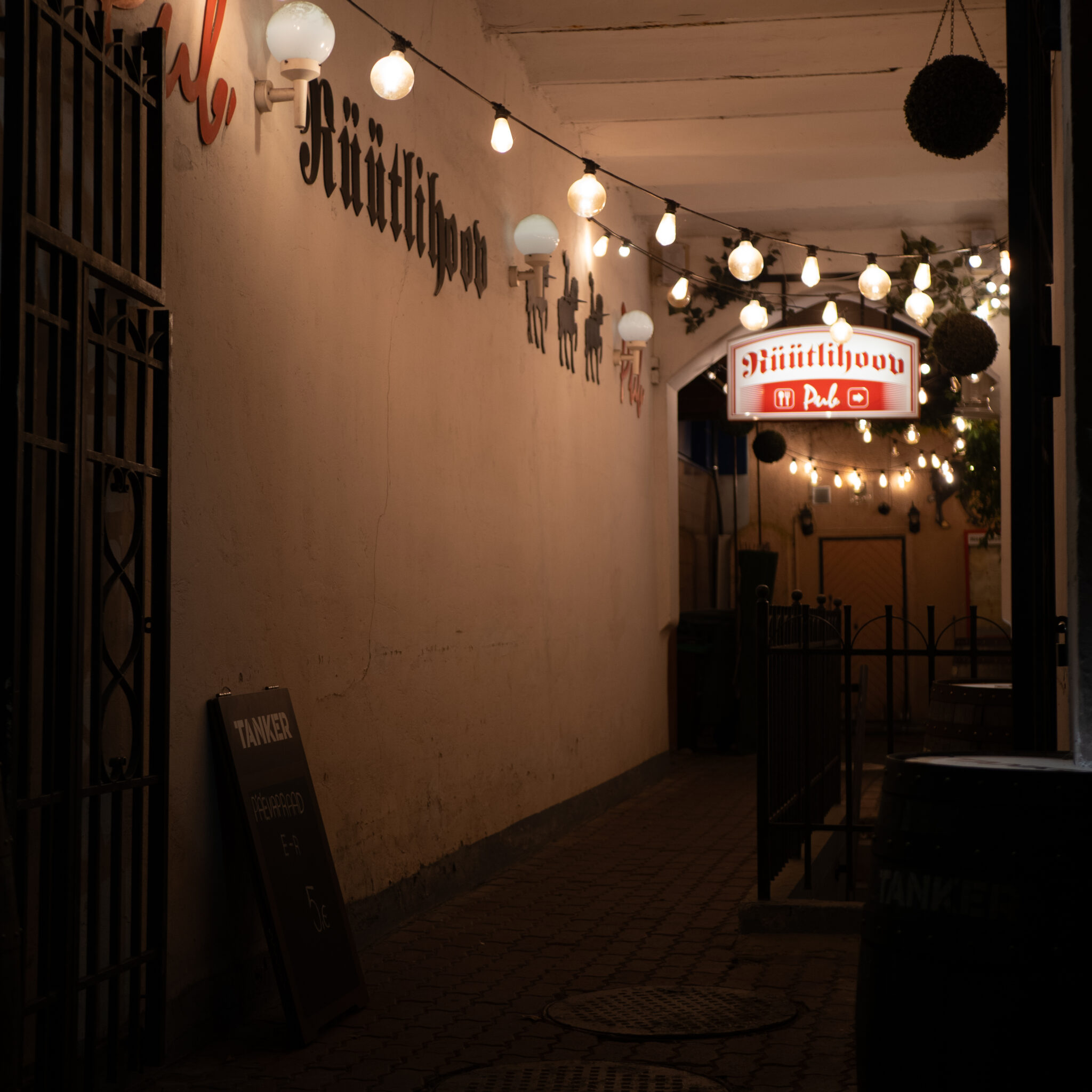 Hämar allee pubi sildi ja tulukestega.