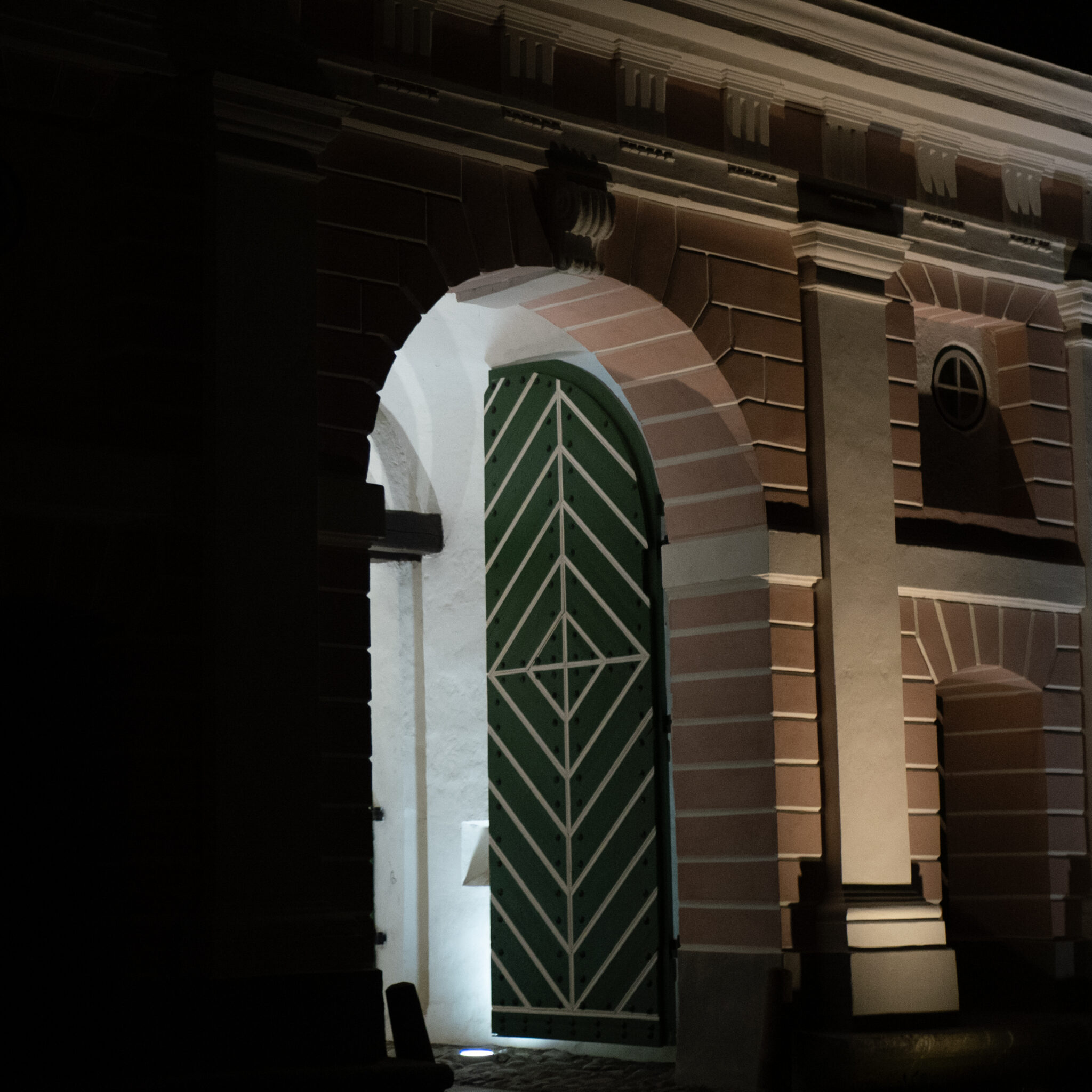 Suur roheline ja valge uks seisab hämaras kaarvõlvis.