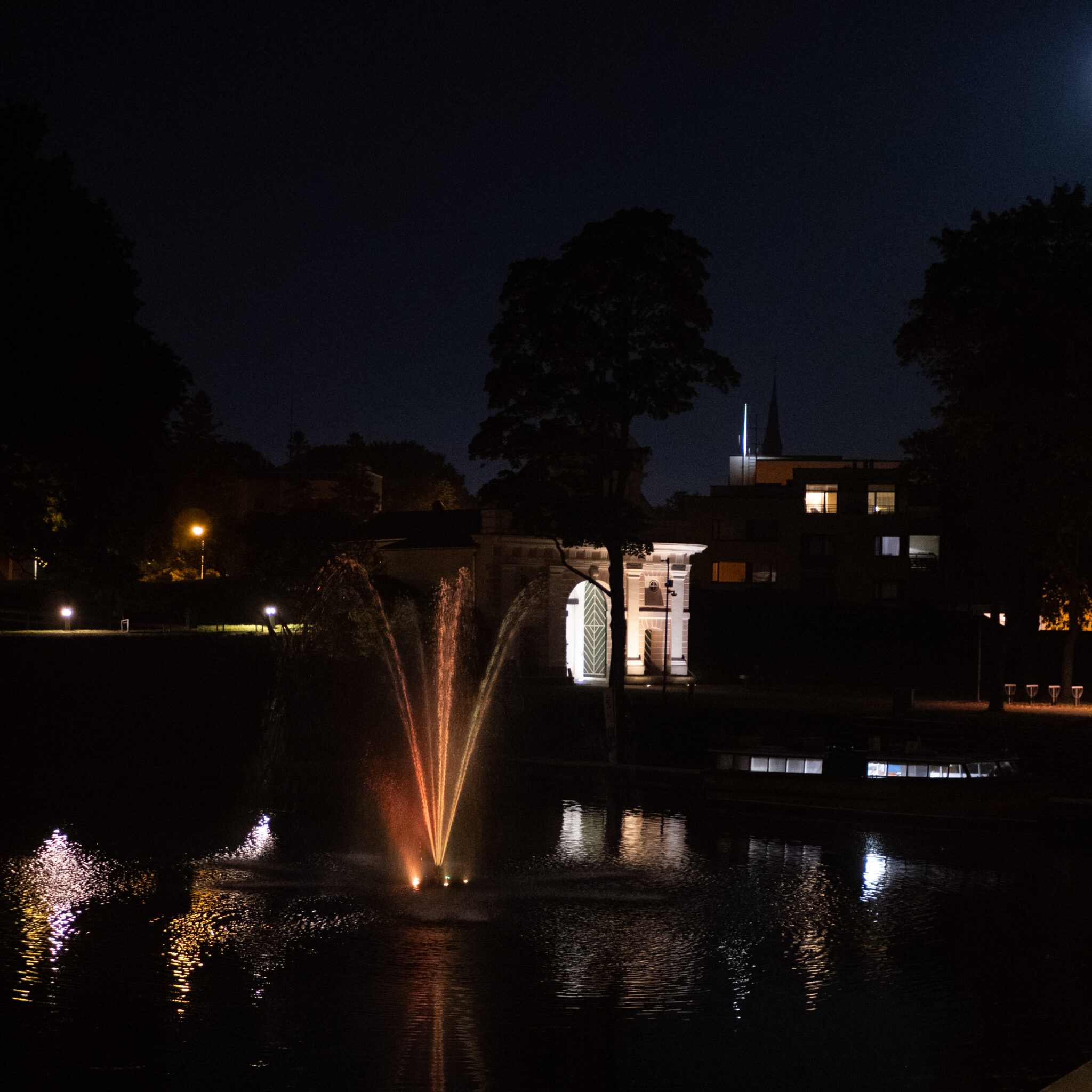 Purskkaev ja valgustatud hoone öösel.