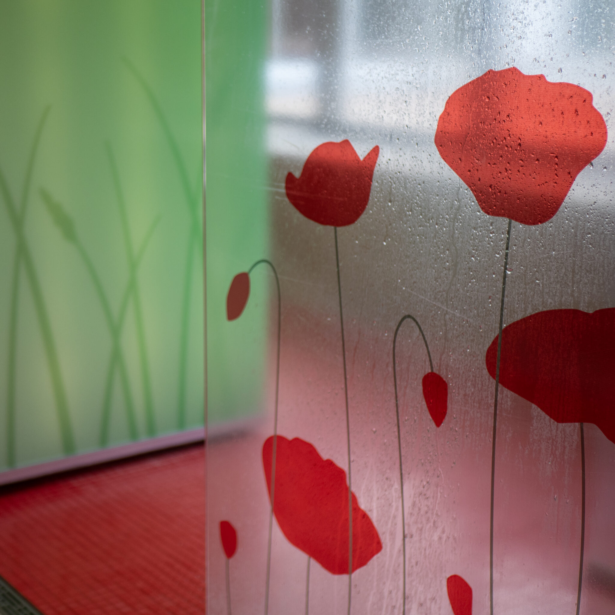 Punased moonid klaasseinal rohelise rohuga taustal.