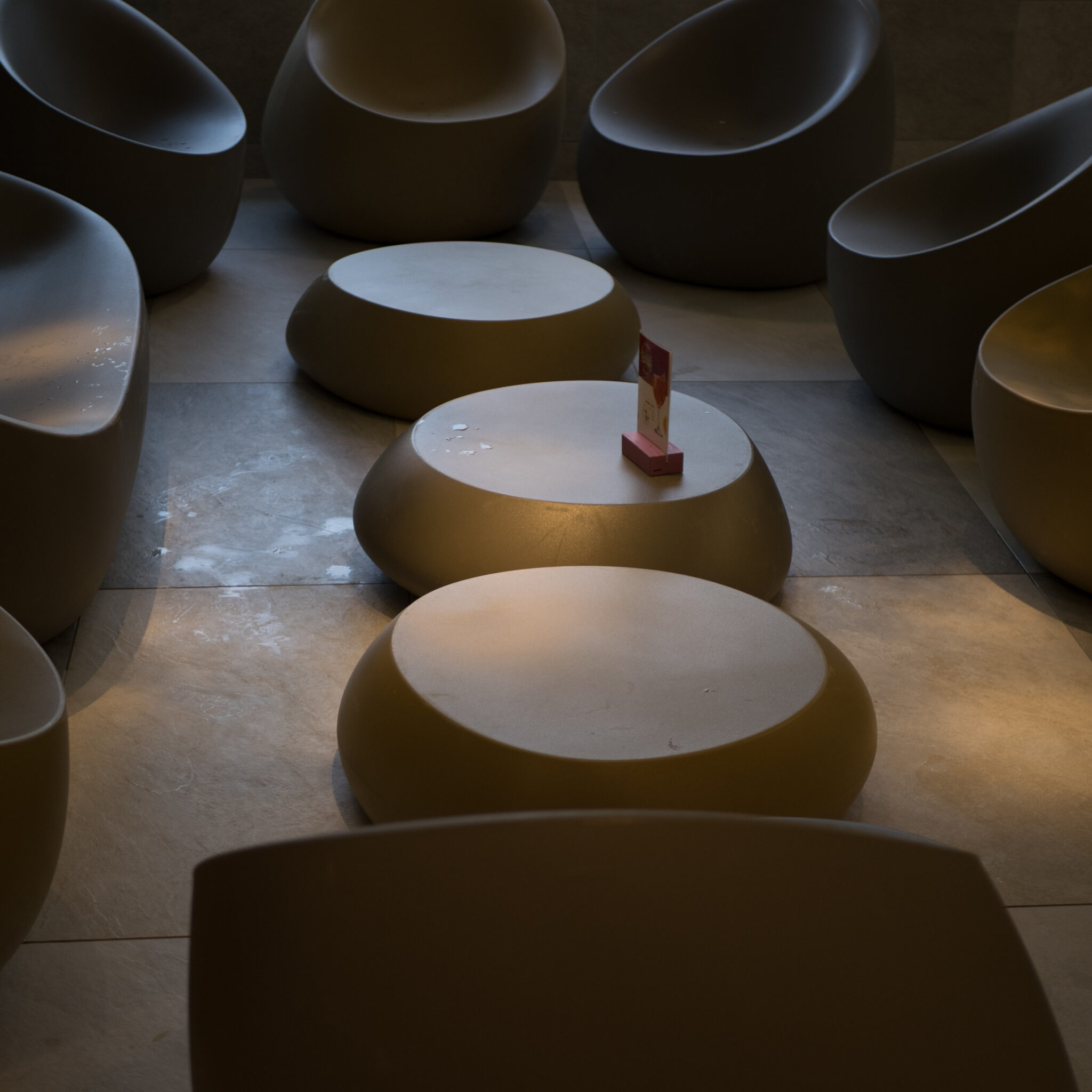 Rida ümaraid laudu ja toole hämaras ruumis.