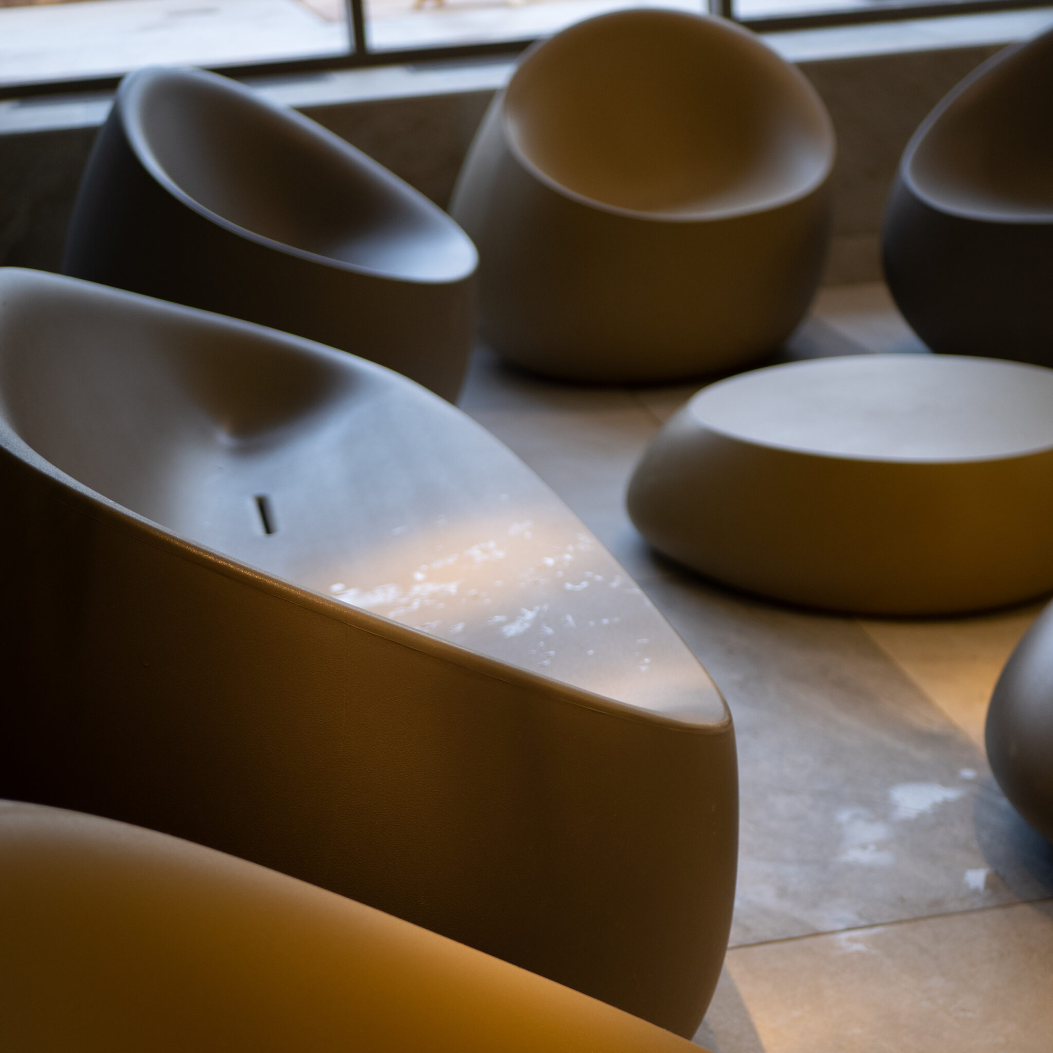 Kaasaegsed hallid kumerad toolid ja ümar laud moodsas ruumis.