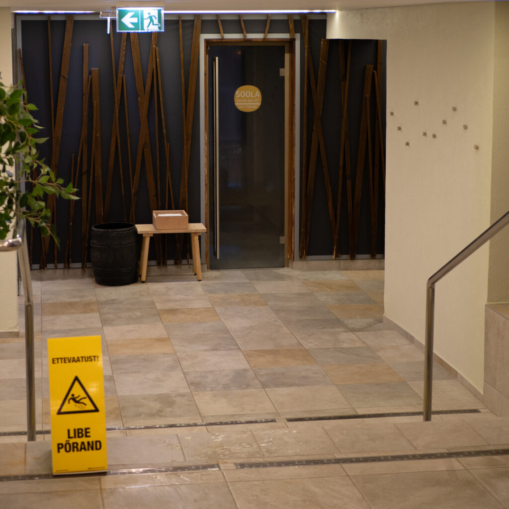 Libedast põrandast hoiatav märk ja uks sauna.