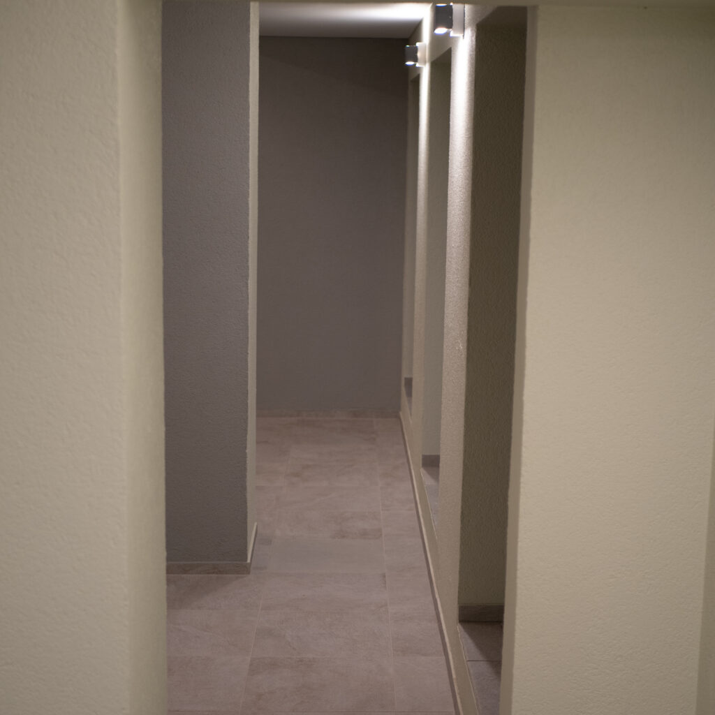 Hämar koridor sammaste ja kohtvalgustitega.