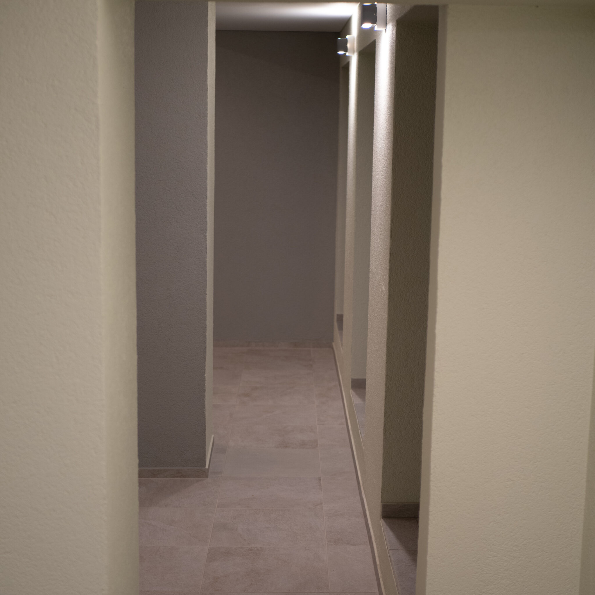 Hämar koridor sammaste ja kohtvalgustitega.
