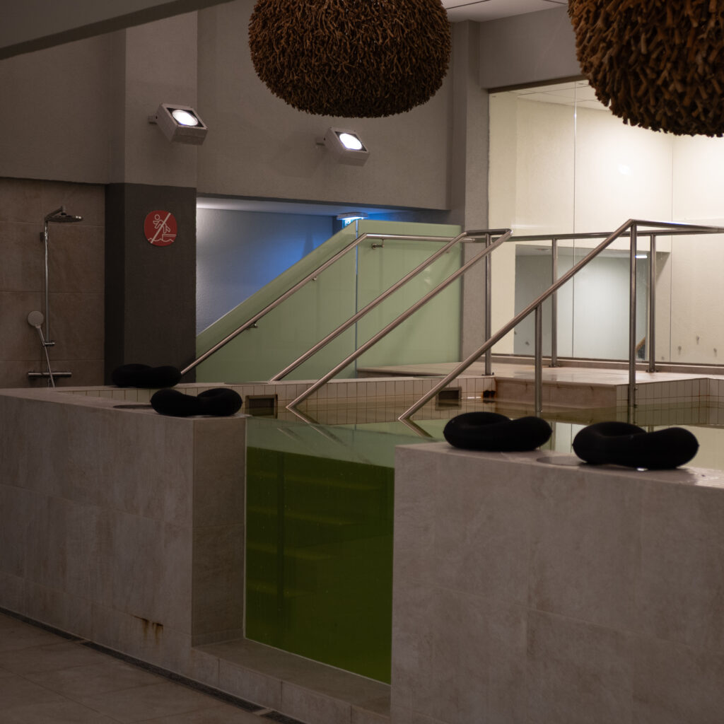 Kaasaegne sisebassein rohelise vee ja mustade ujuvate istmetega.